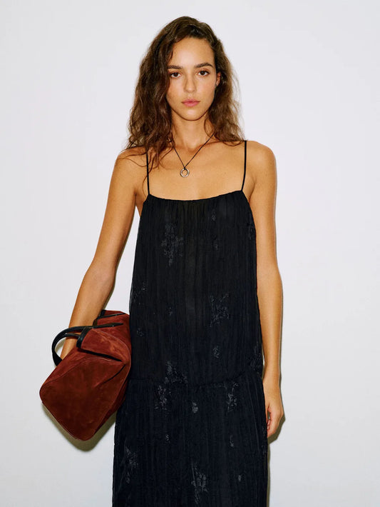 Woman wearing a black dress holding a red bag against a white background