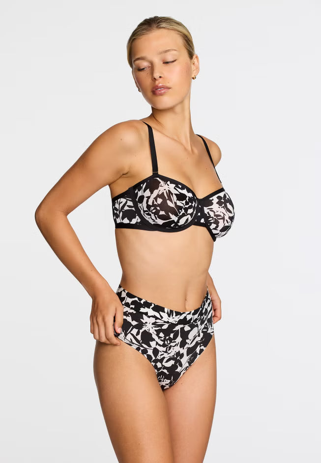 Woman wearing a black and white floral bikini on a light gray background