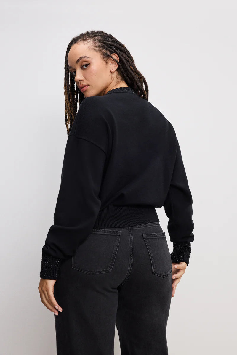 Person wearing a black sweater and black pants against a white background