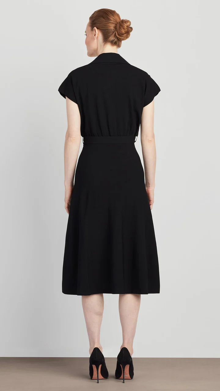 Woman wearing a black dress standing against a plain background