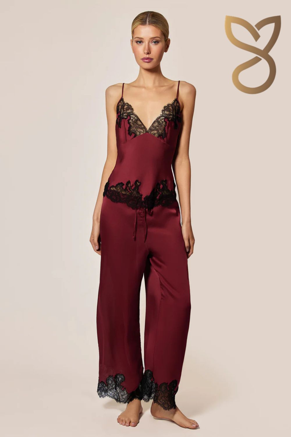 Woman wearing burgundy lace pajama set on a beige background