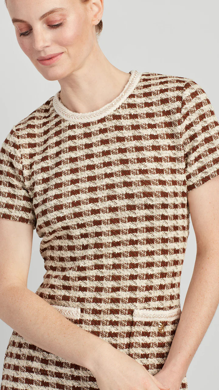 Woman wearing a brown and beige checkered dress against a light gray background