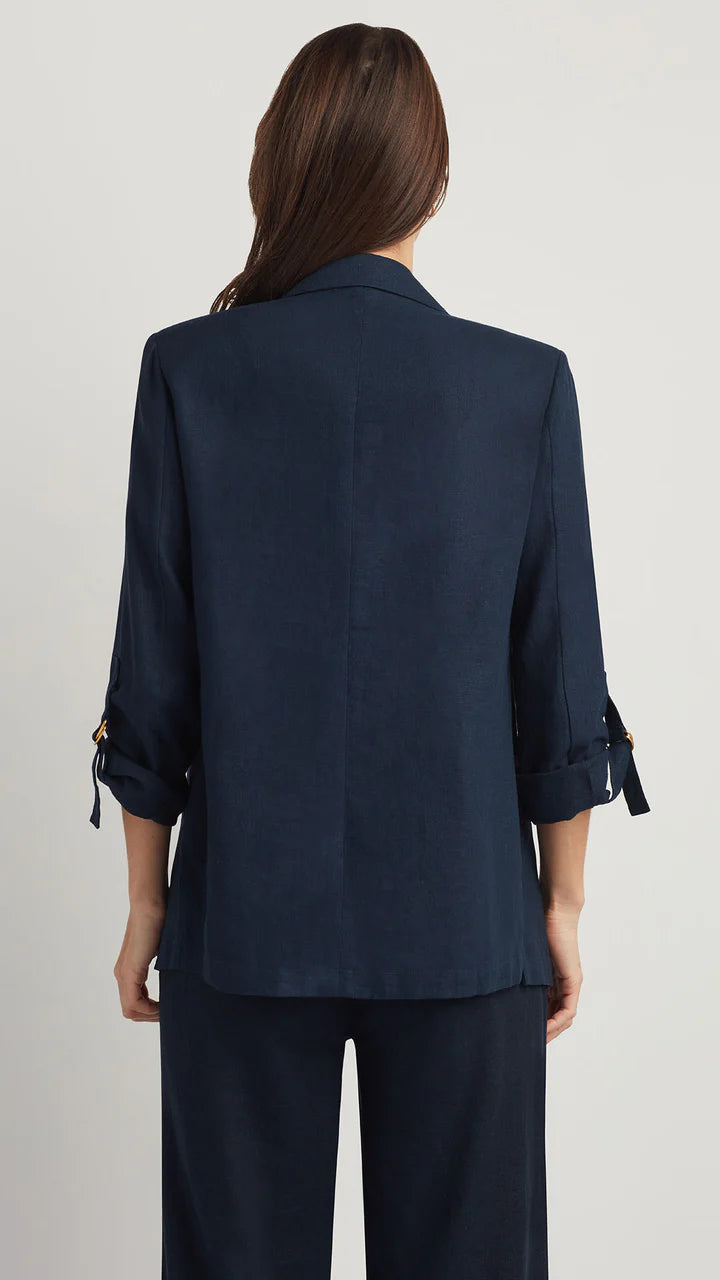 Person wearing a navy blue blazer and pants on a light gray background