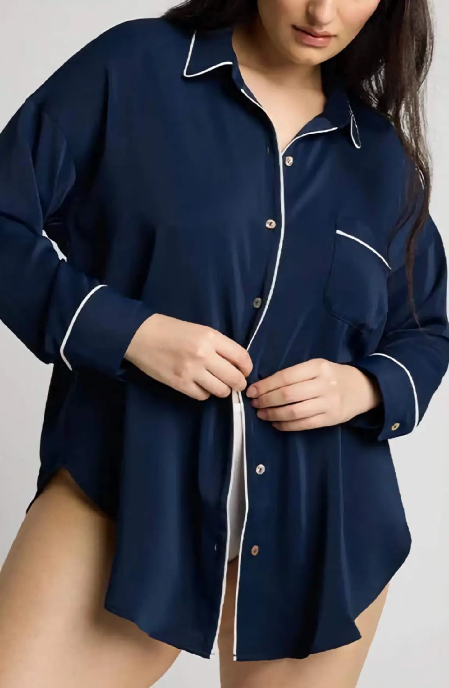Navy blue pajama top with white piping on a plain background