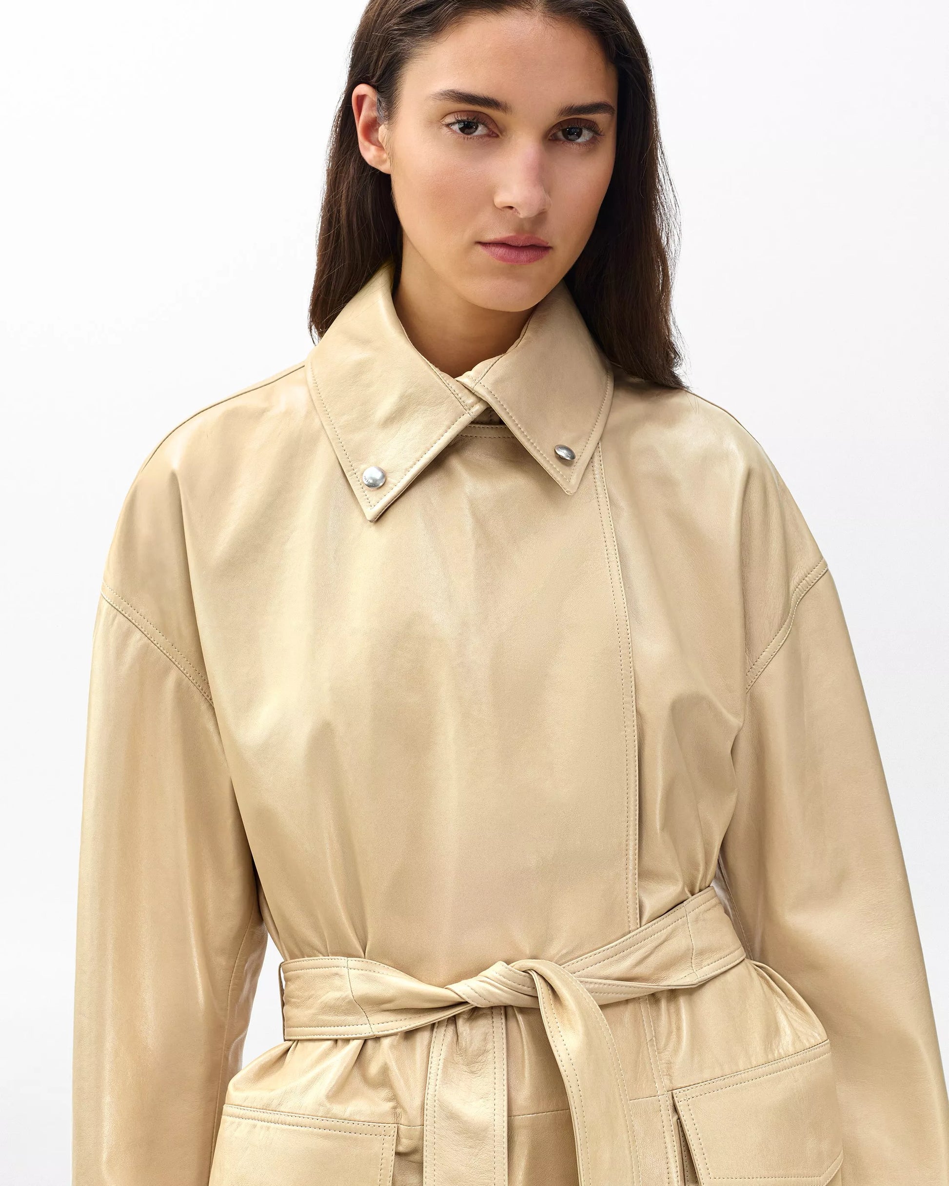 Woman wearing a beige trench coat on a white background