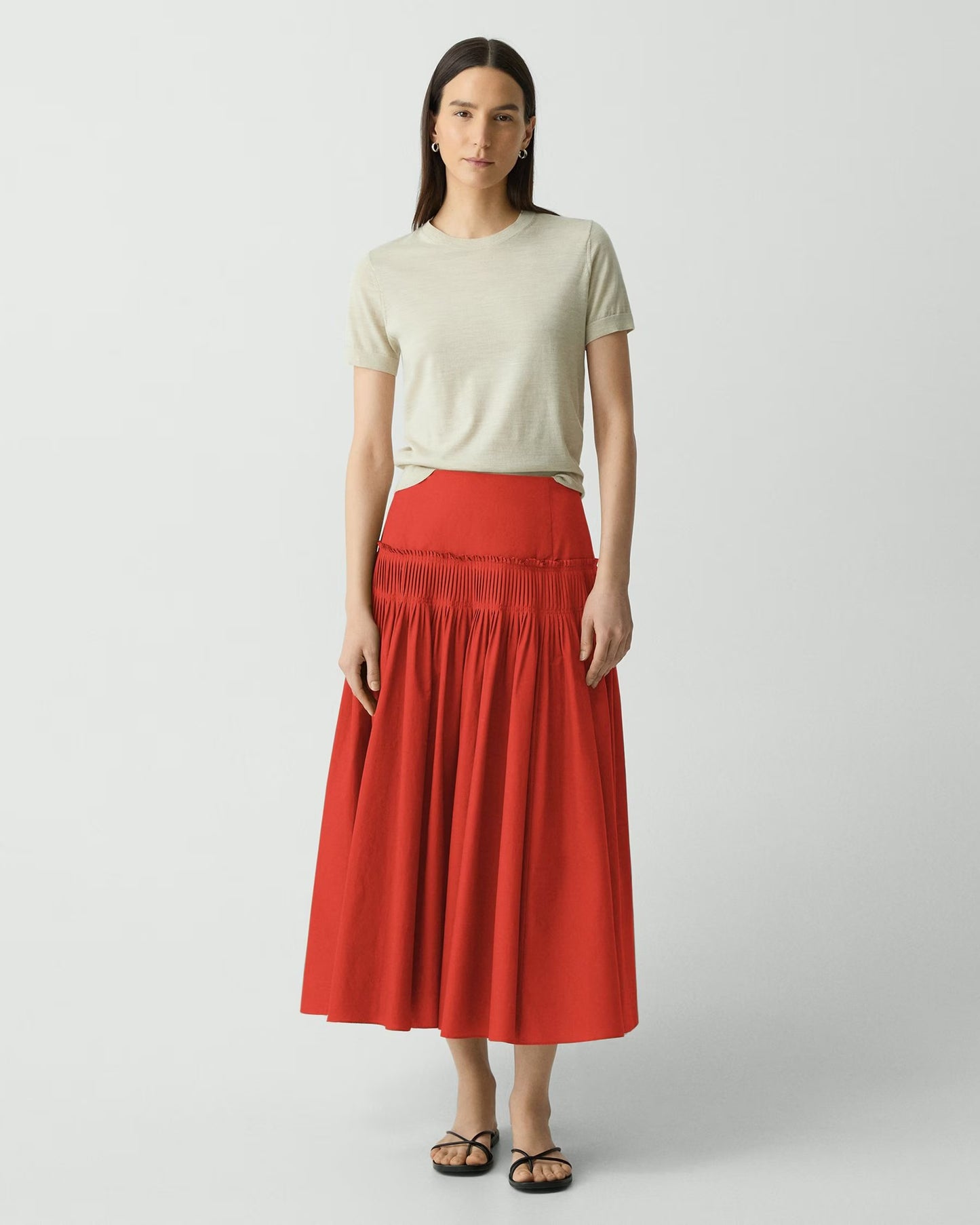 Woman wearing a red skirt and beige top on a white background