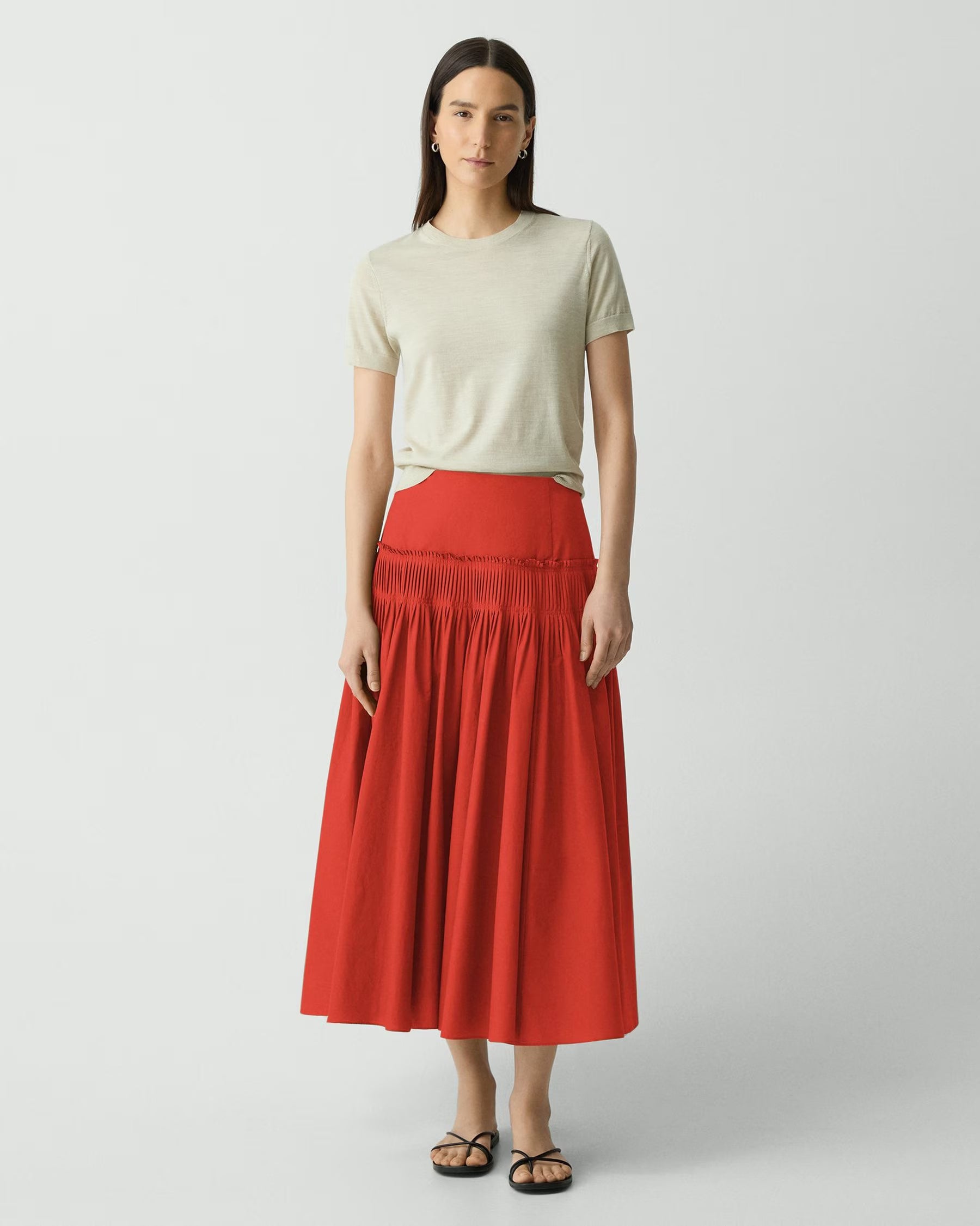 Woman wearing a red skirt and beige top on a white background