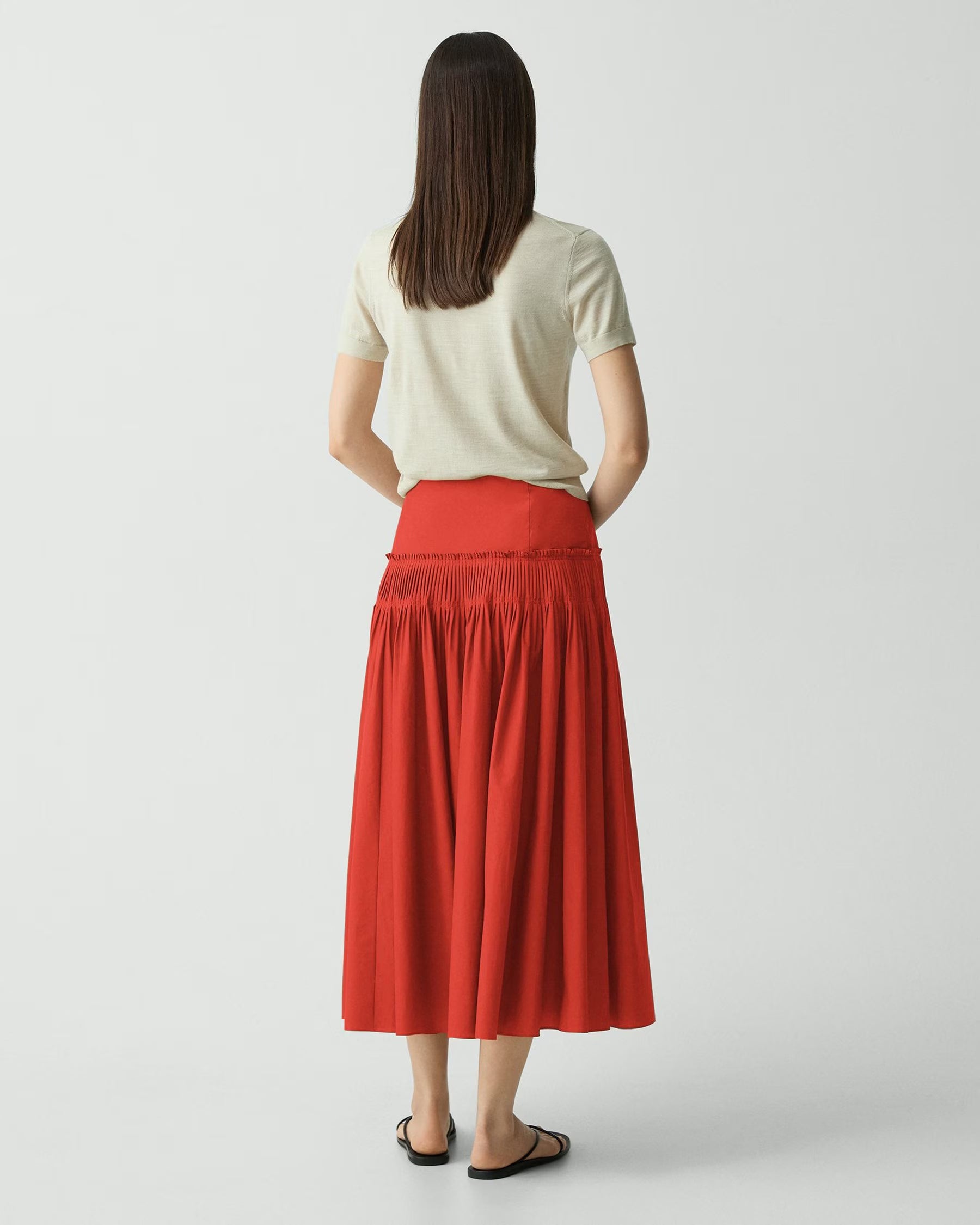 Woman wearing a red skirt and white top on a plain background