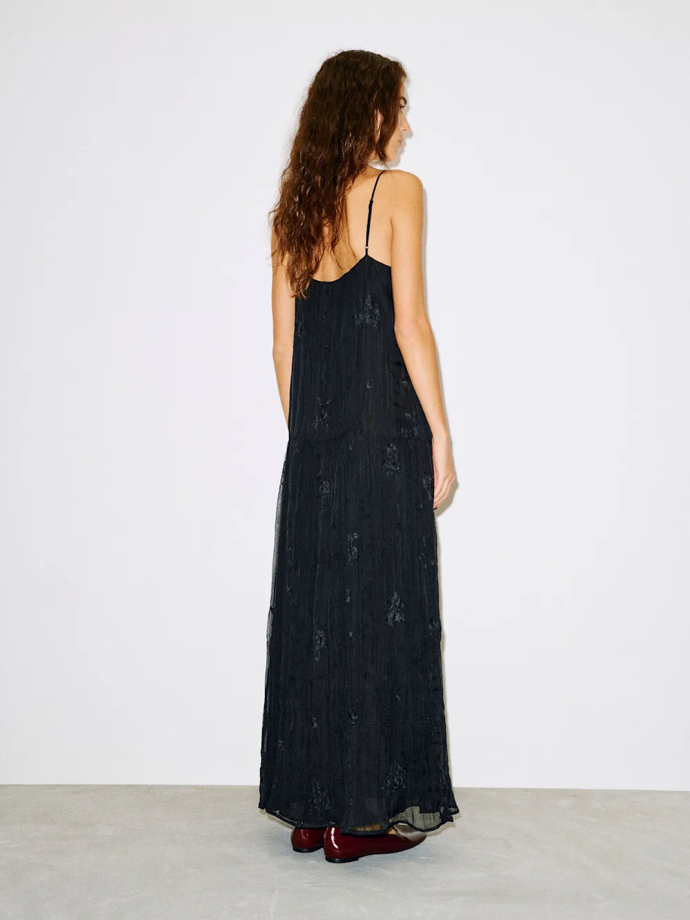 Woman wearing a black dress with thin straps against a white background