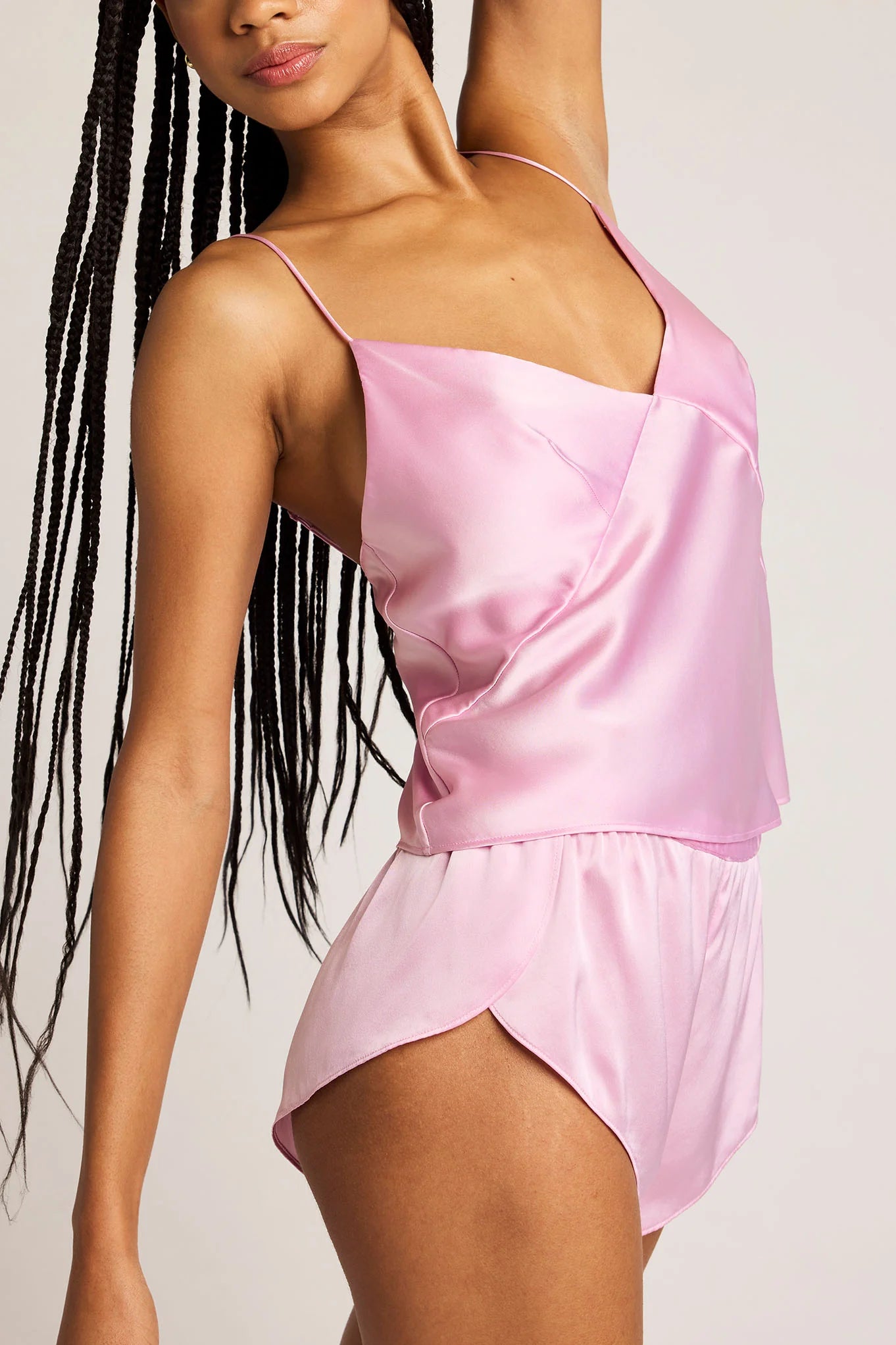 Woman wearing a pink satin dress against a plain background