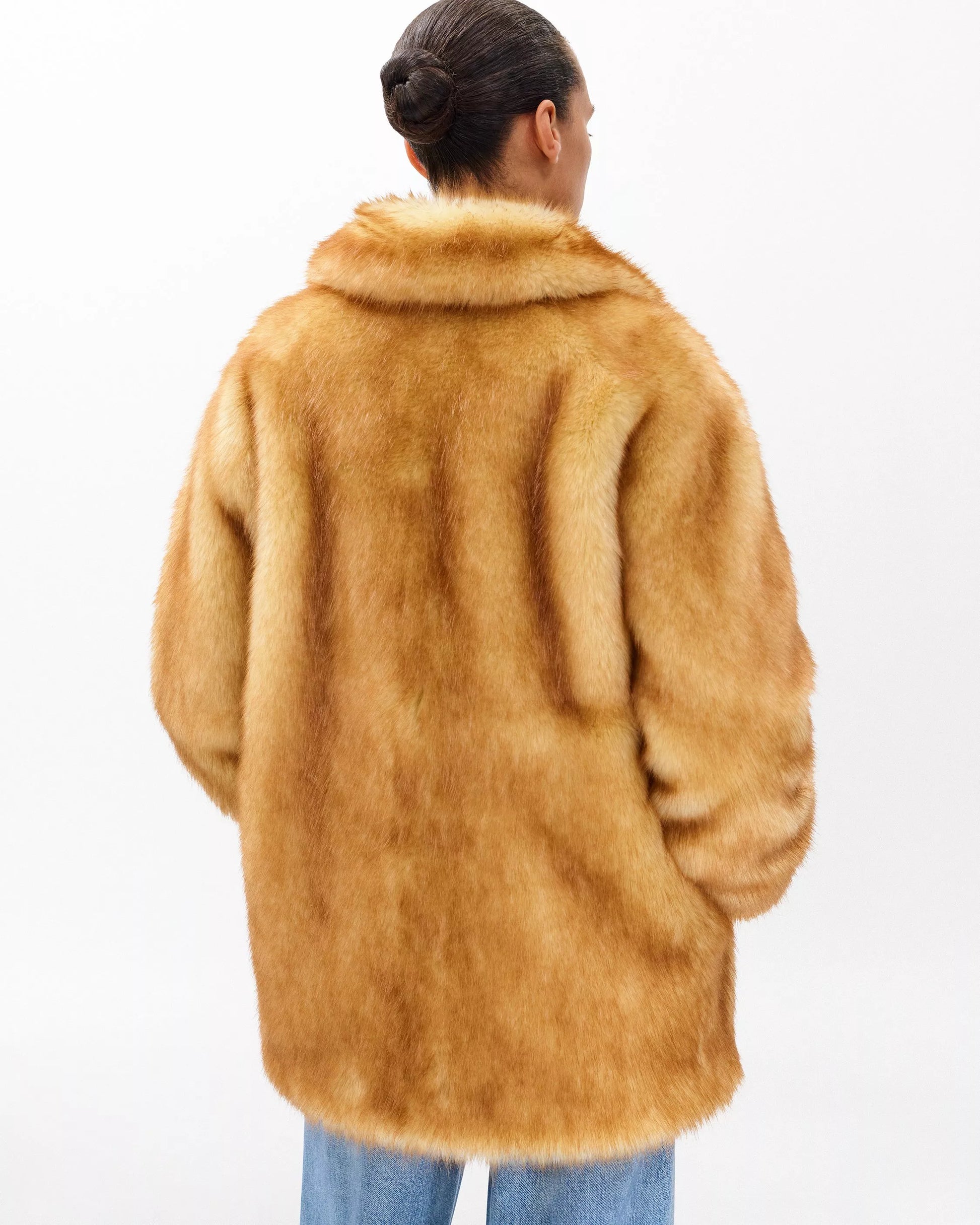 Person wearing a brown faux fur coat on a white background