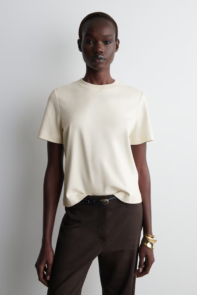 Sovereign woman in undyed organic cotton essential tee - silent authority in urban setting - Lux & Motion archive-worthy wardrobe foundation