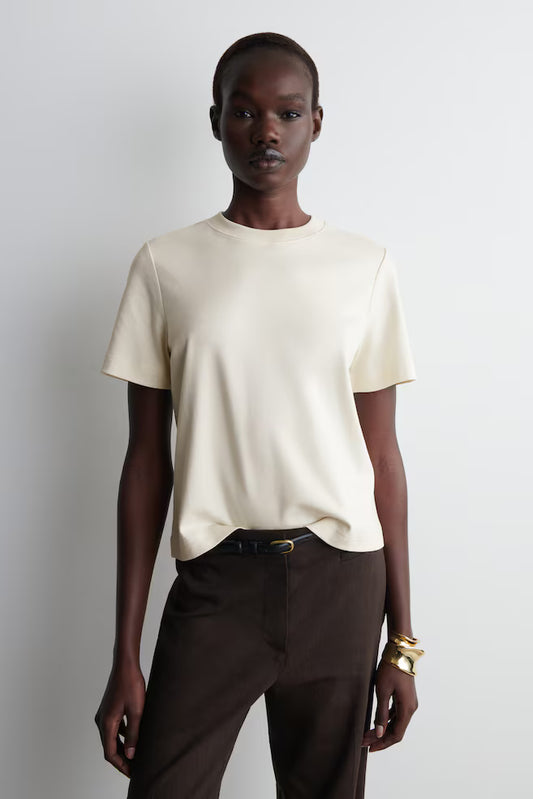 Sovereign woman in undyed organic cotton essential tee - silent authority in urban setting - Lux & Motion archive-worthy wardrobe foundation