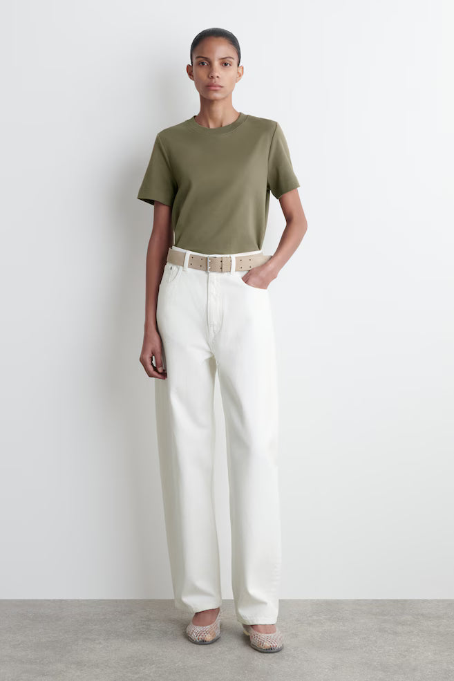 Person wearing a green t-shirt and white pants against a plain background
