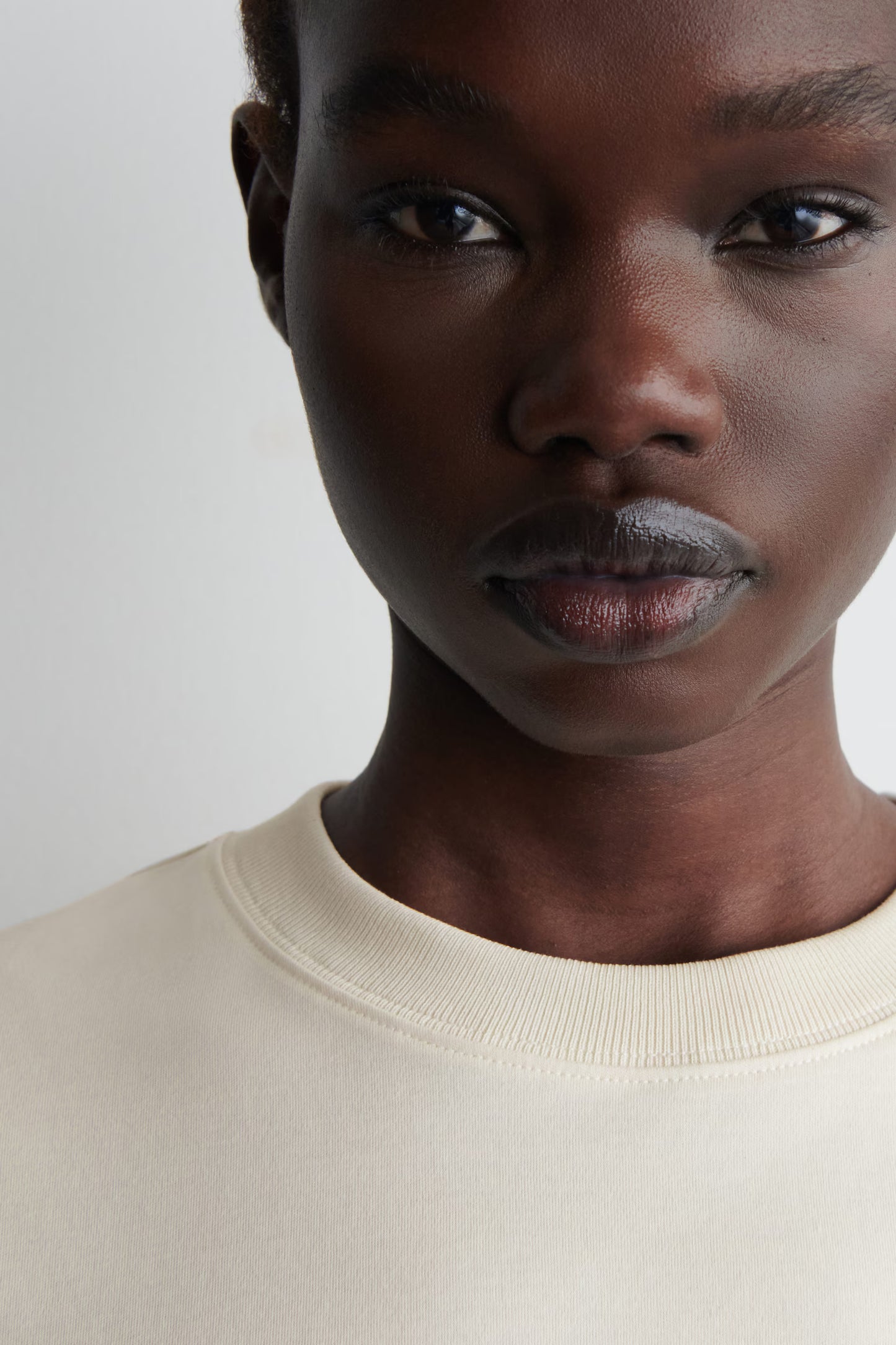 Close-up of a person wearing a beige sweater against a plain background