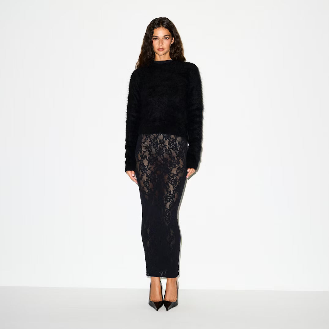 Woman wearing a black sweater and lace skirt on a white background