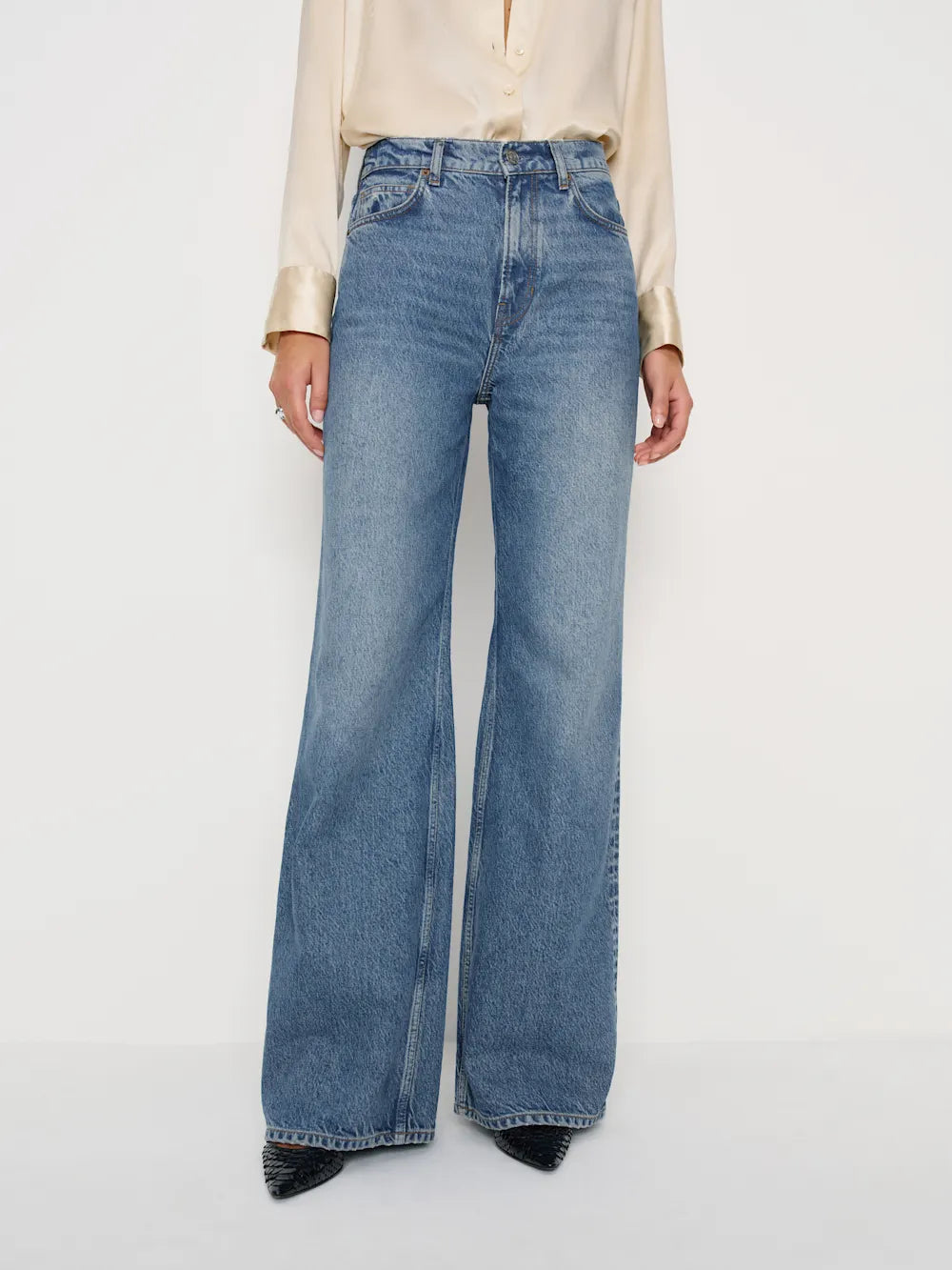 Blue flared jeans worn by a person on a white background