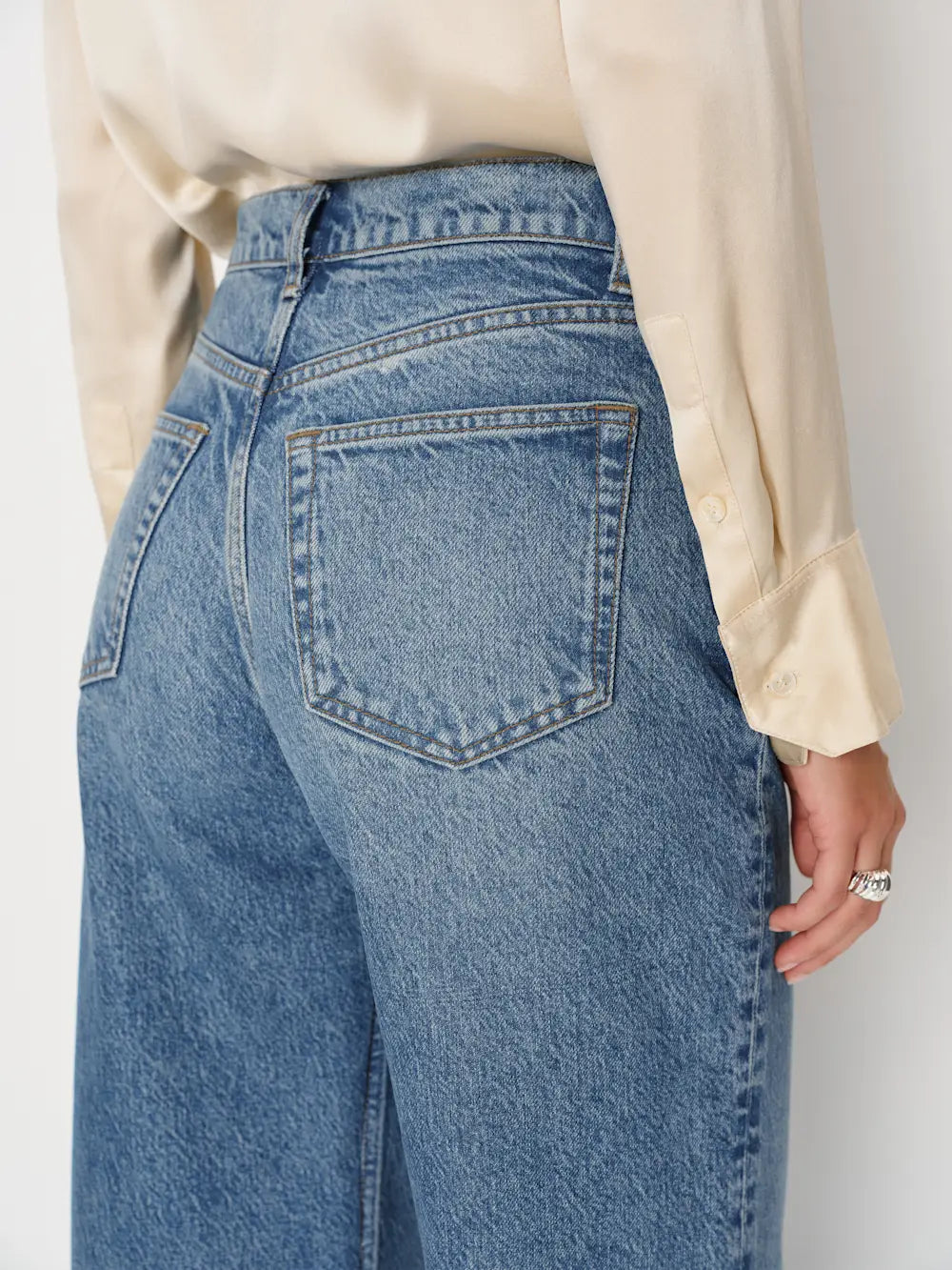Person wearing blue jeans with a plain background