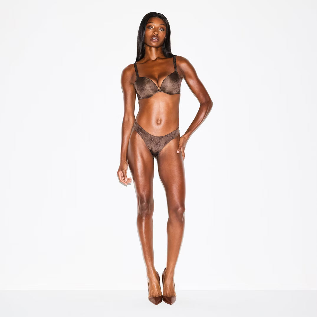 Model wearing a brown lingerie set on a white background