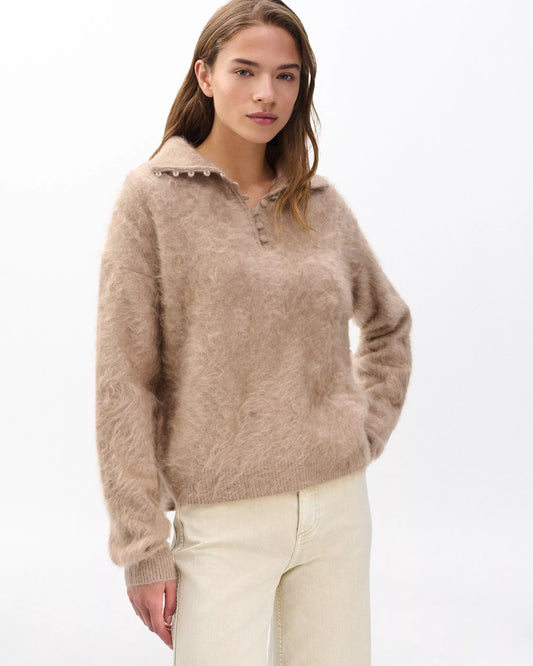 Woman wearing a beige sweater with a white background