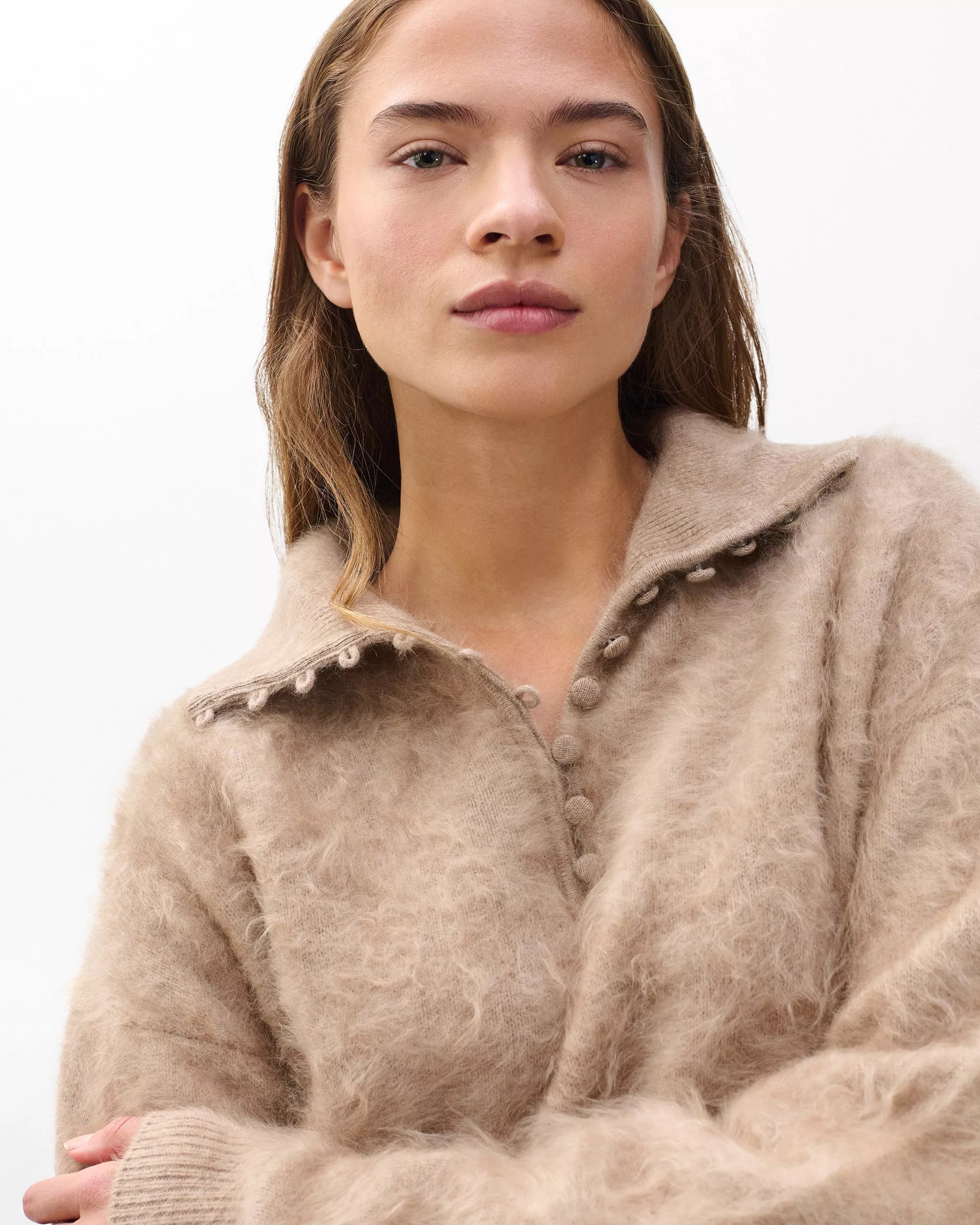 Woman wearing a beige knitted cardigan against a white background