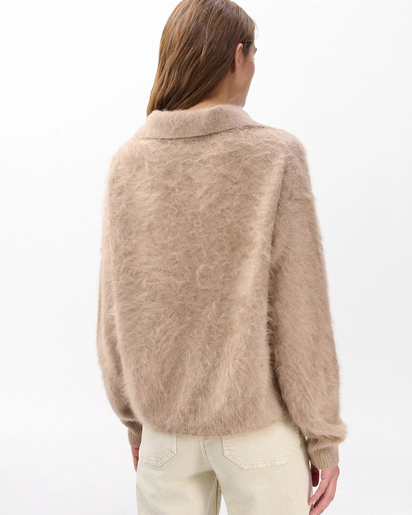 Person wearing a beige sweater on a white background