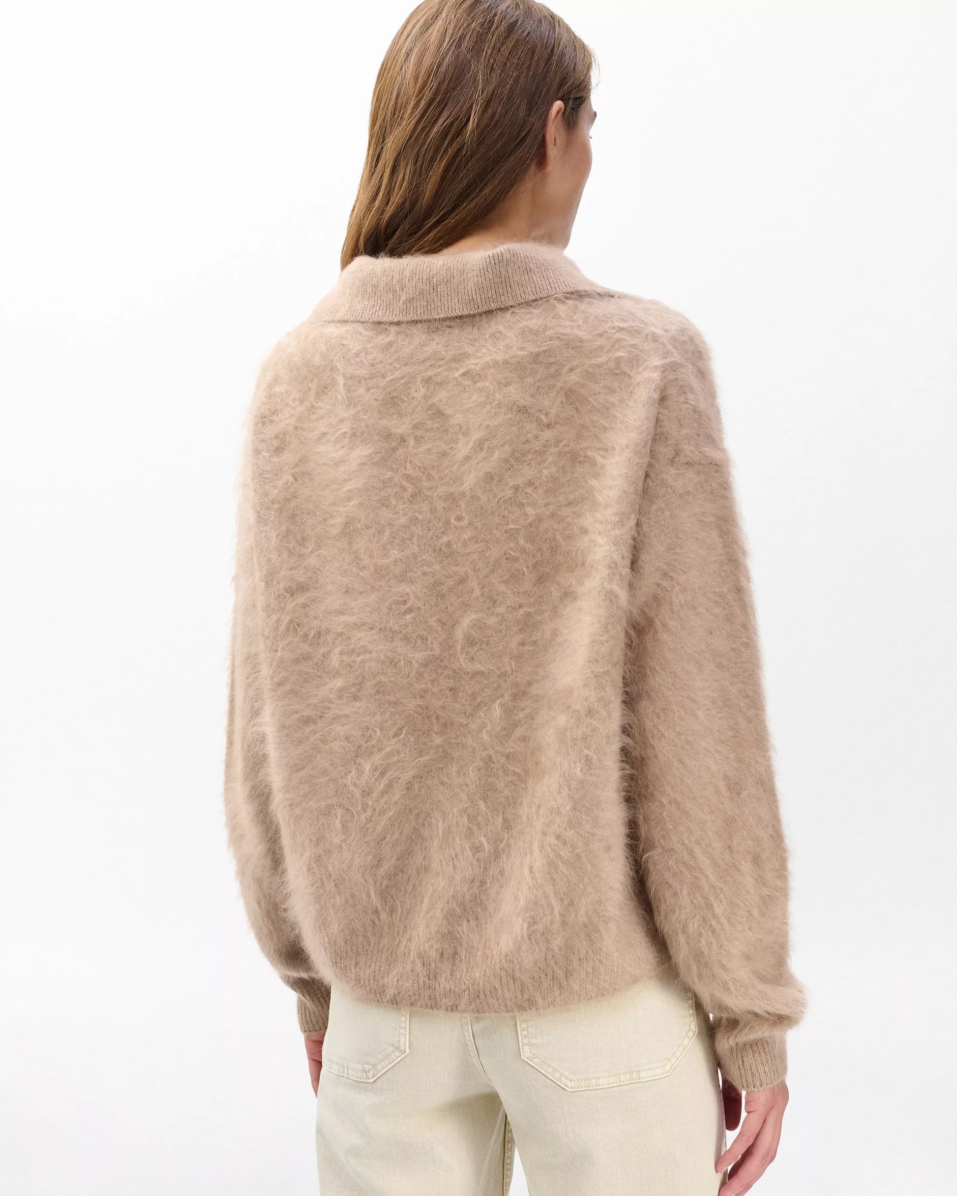 Person wearing a beige sweater on a white background