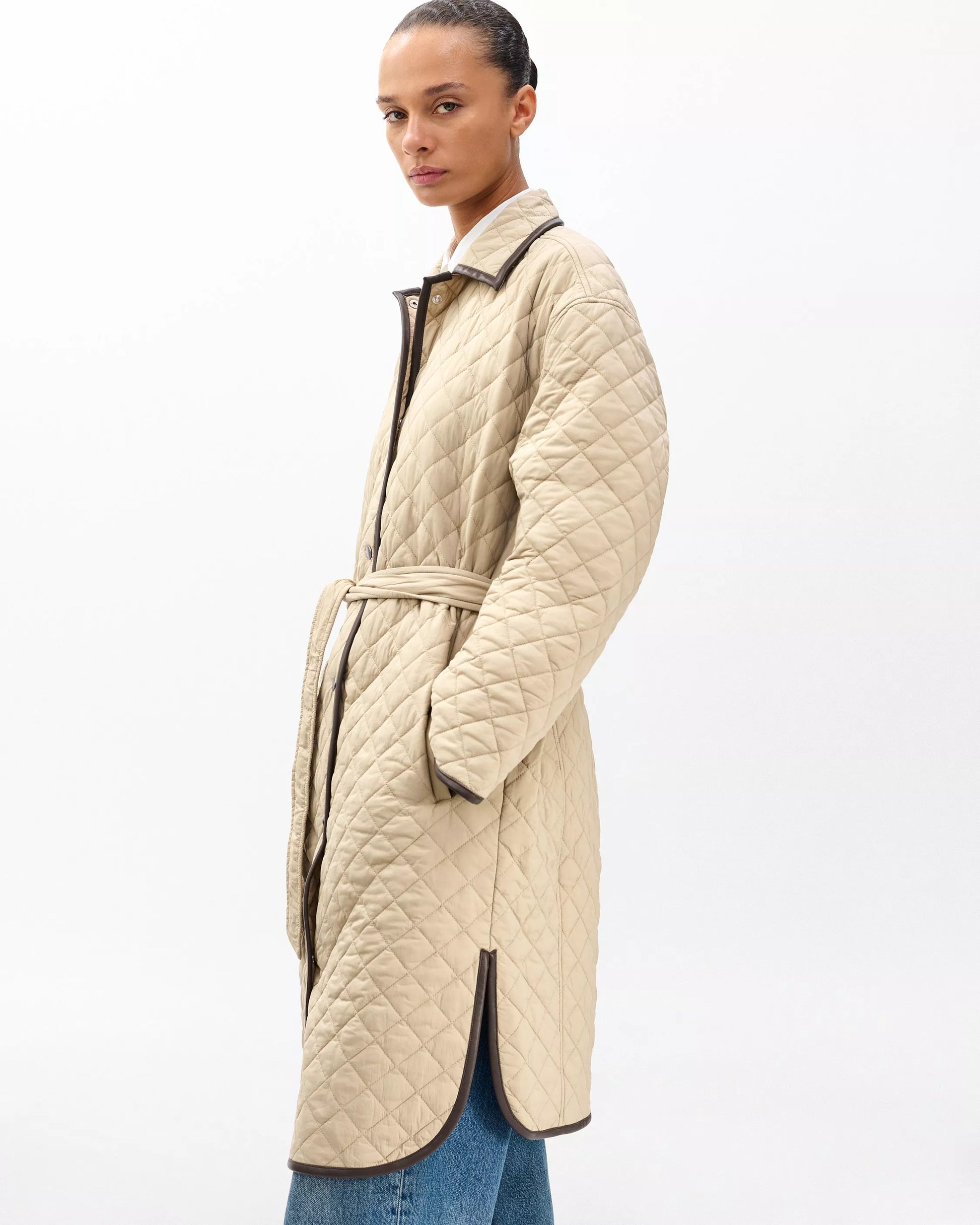 Woman wearing a beige quilted coat on a white background