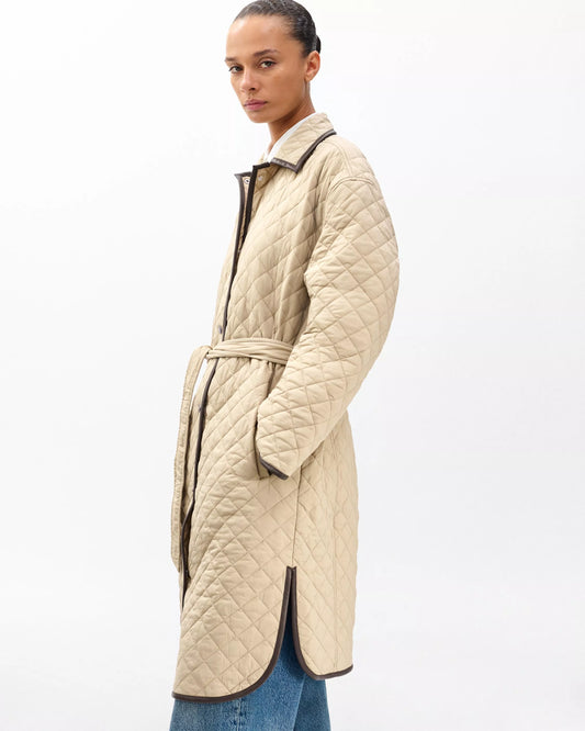 Woman wearing a beige quilted coat on a white background