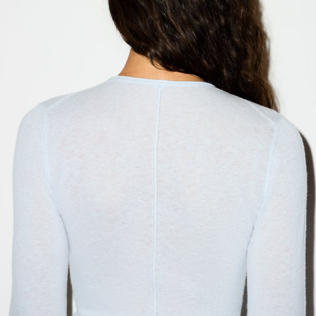 Light blue long-sleeve top worn by a person on a white background
