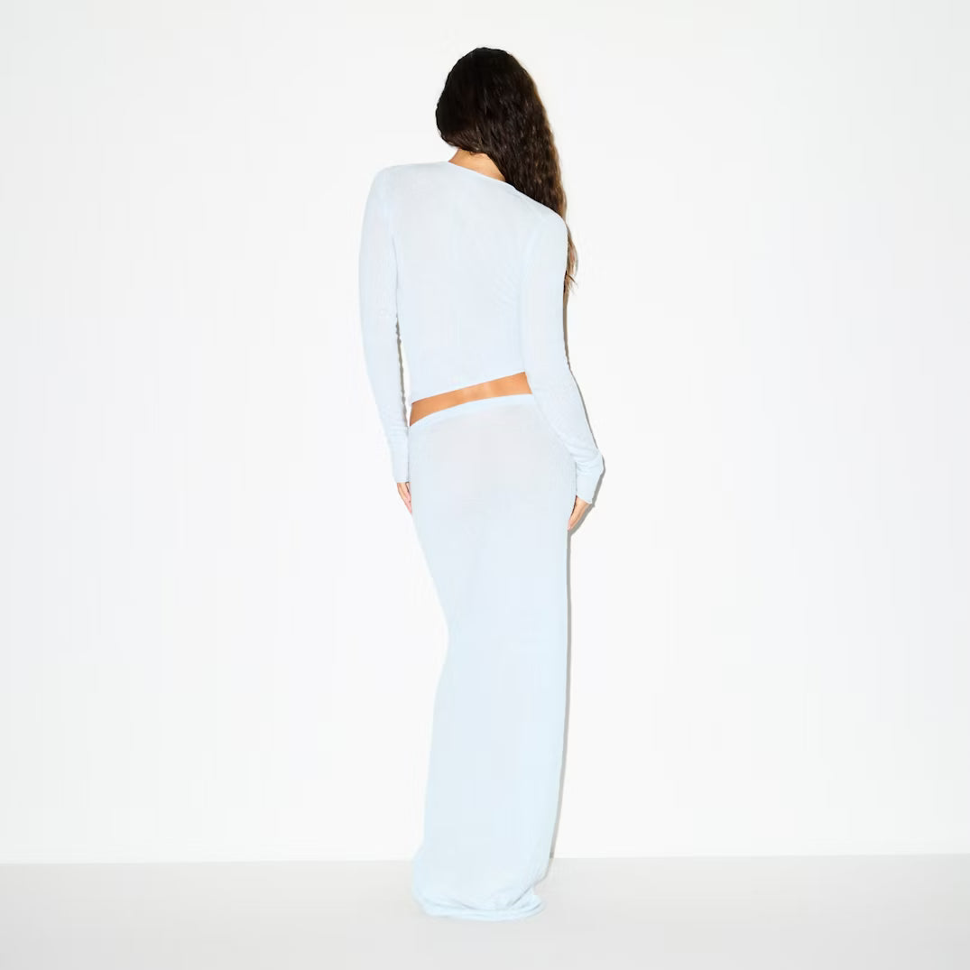 Woman wearing a white outfit with a brown accent on a white background