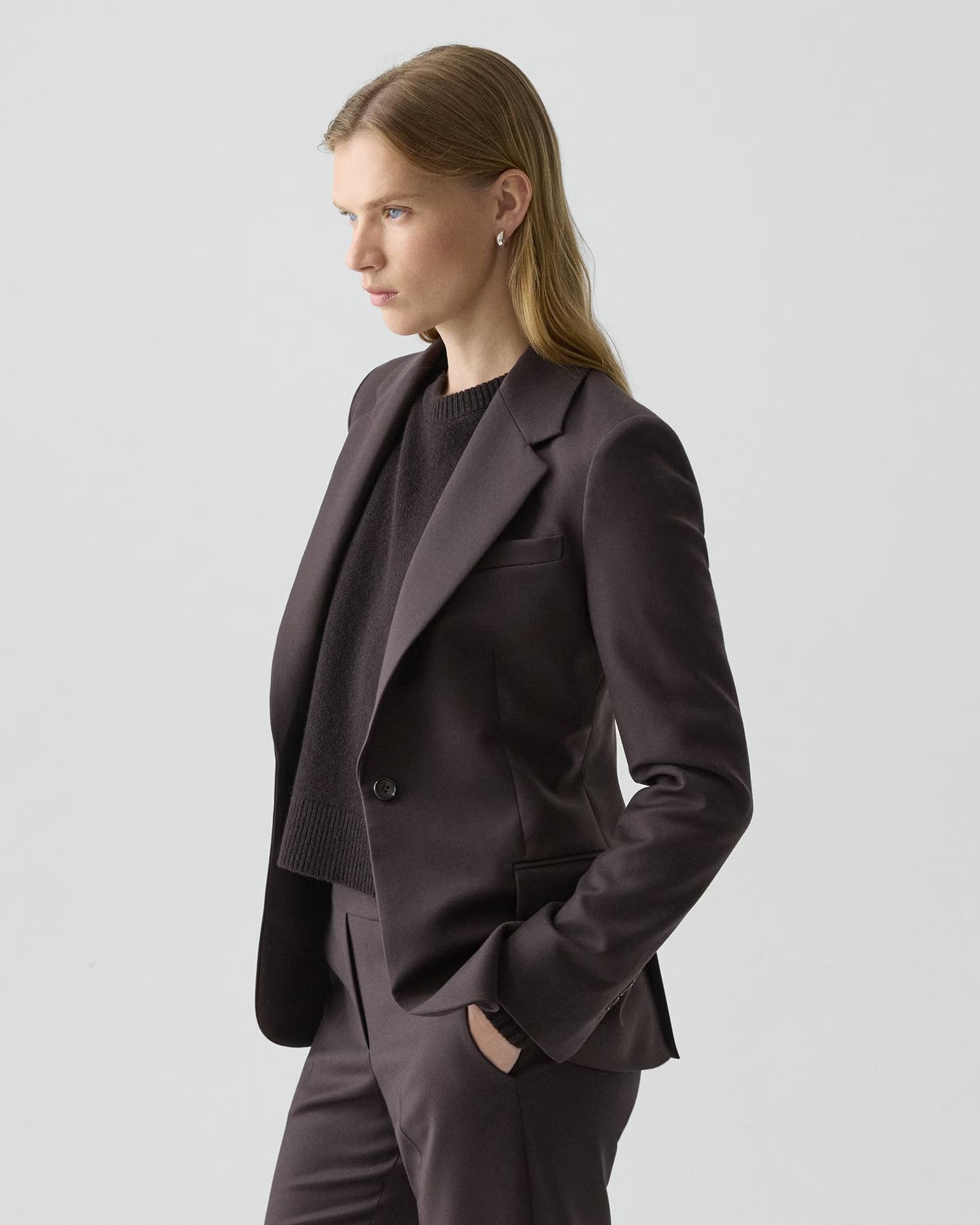 Woman wearing a dark brown suit on a light gray background