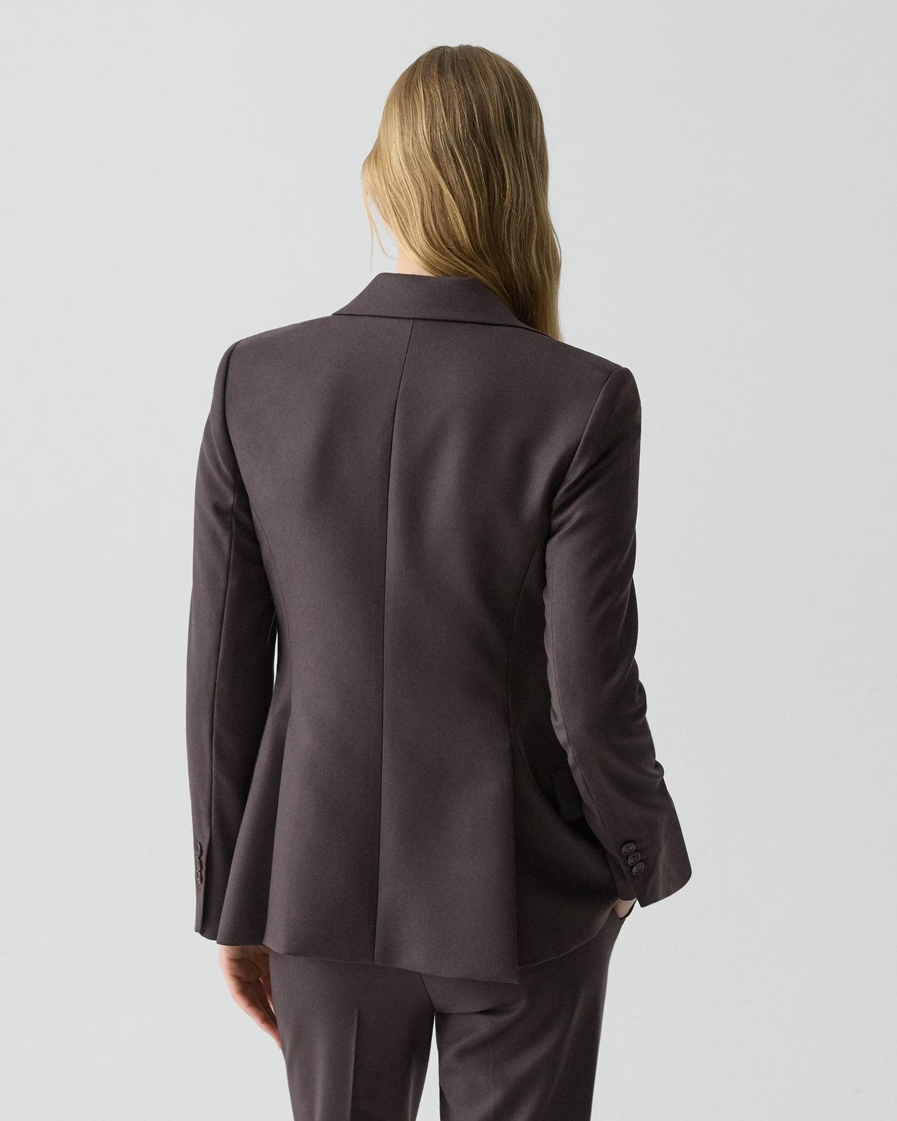 Woman wearing a dark gray suit on a light gray background