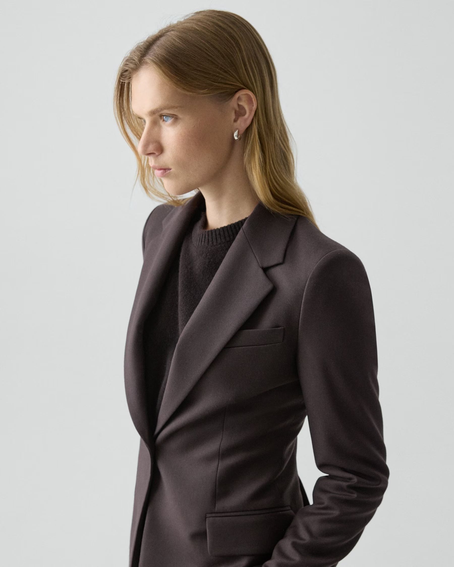 Woman wearing a brown blazer against a plain background