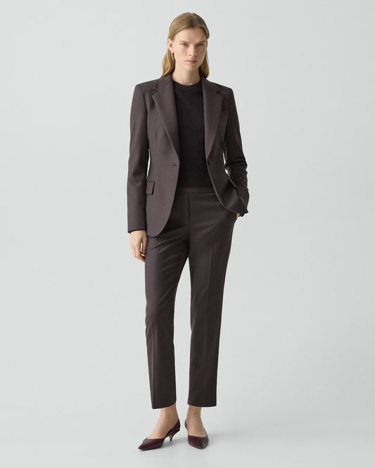 Woman wearing a dark brown suit on a light gray background