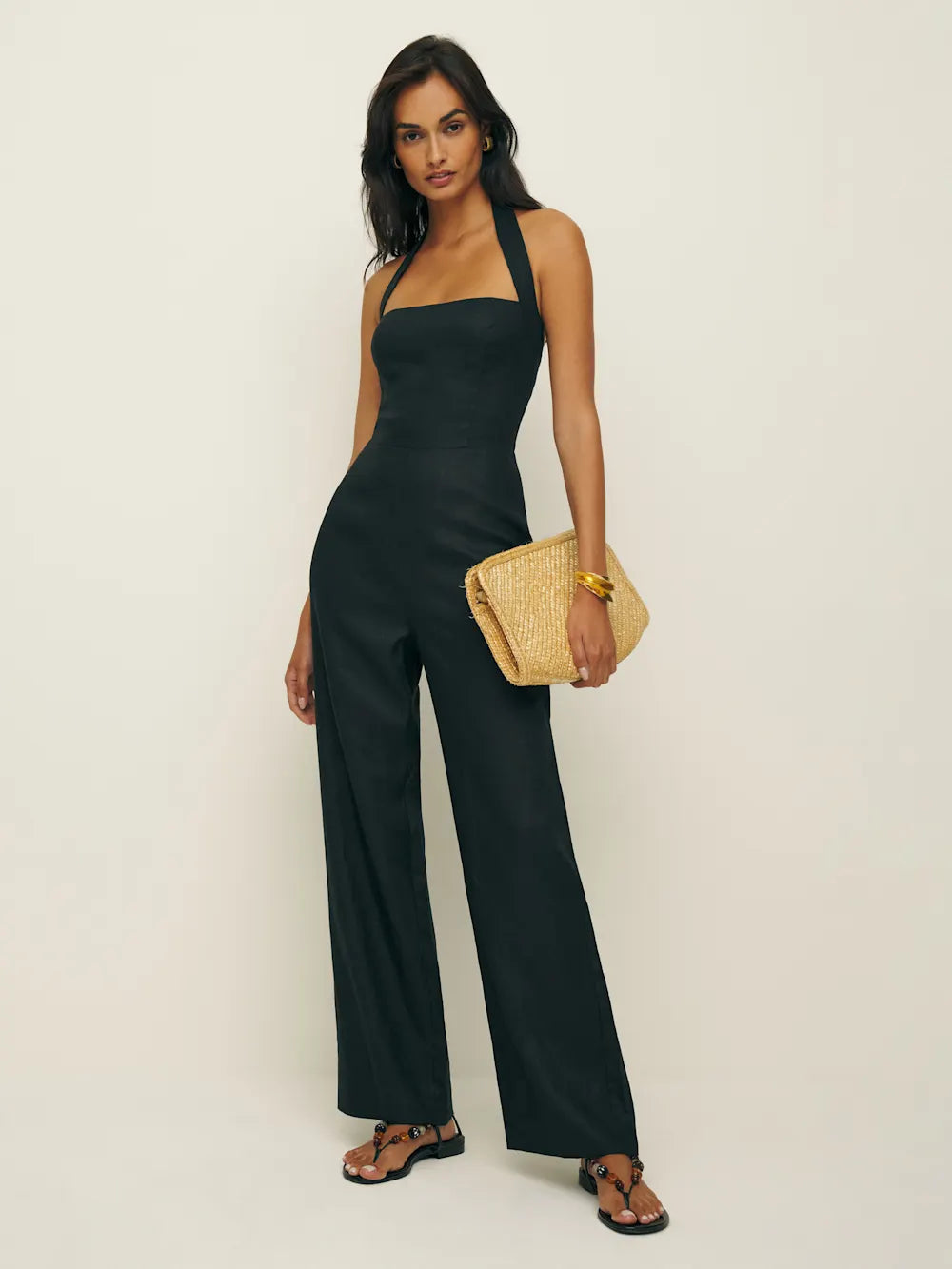 Woman in black Malika Linen Jumpsuit standing in a sunlit Hudson Valley orchard at golden hour, linen draping softly, embodying sovereign autumn ritual and archival elegance.