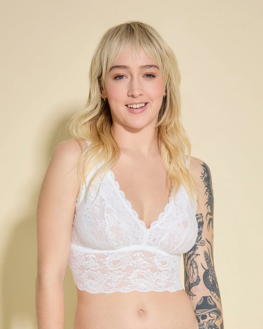 Woman wearing a white lace bra against a beige background