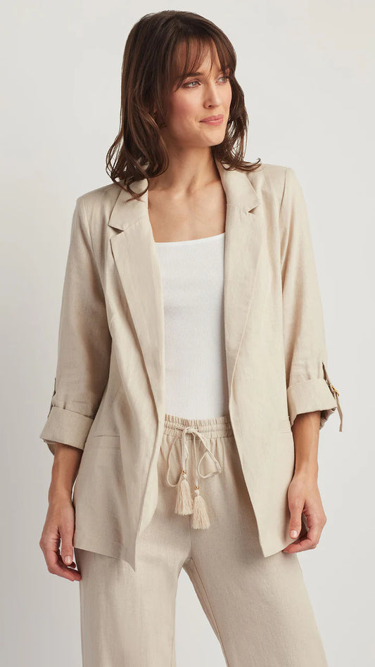 Woman wearing a beige blazer and pants set on a plain background