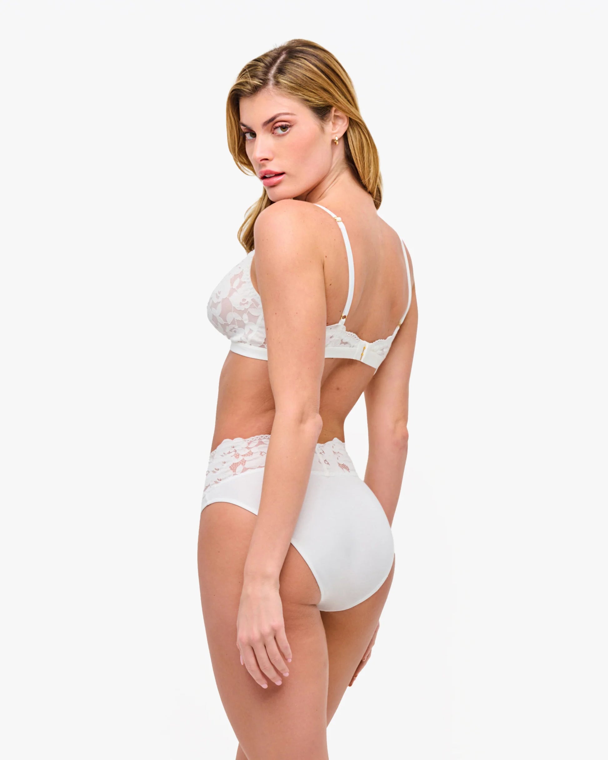 Woman wearing a white lace lingerie set on a white background