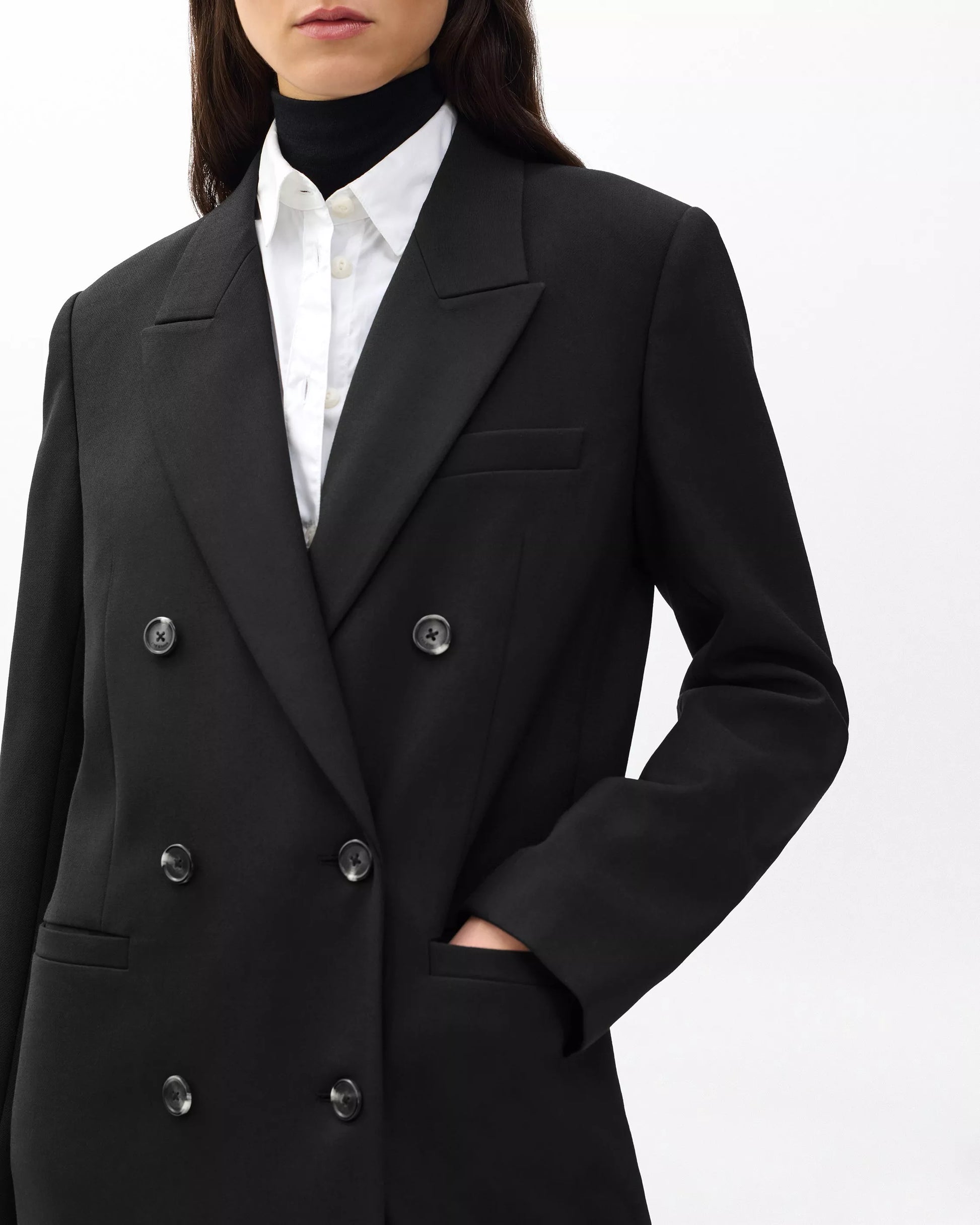 Black double-breasted coat worn by a person on a white background