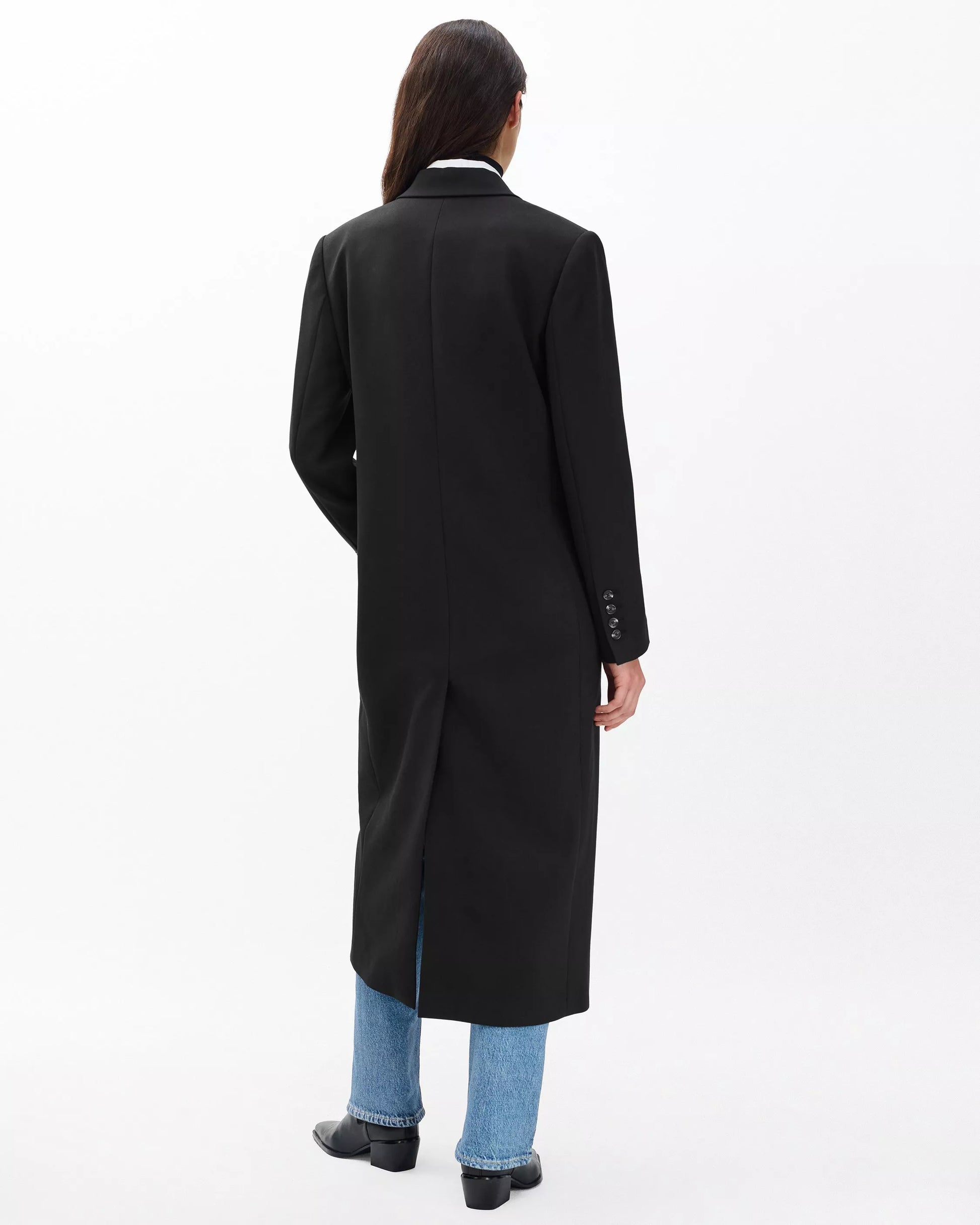 Person wearing a long black coat on a white background
