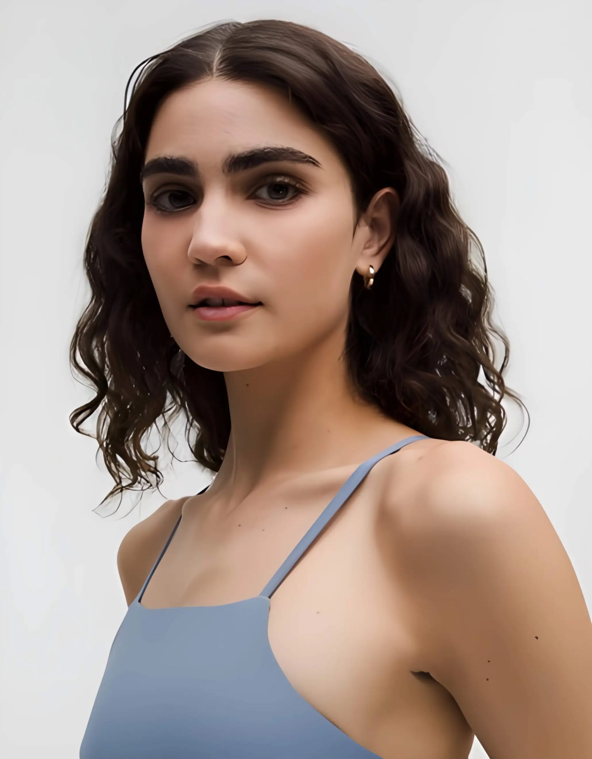 Woman wearing a light blue tank top against a plain background