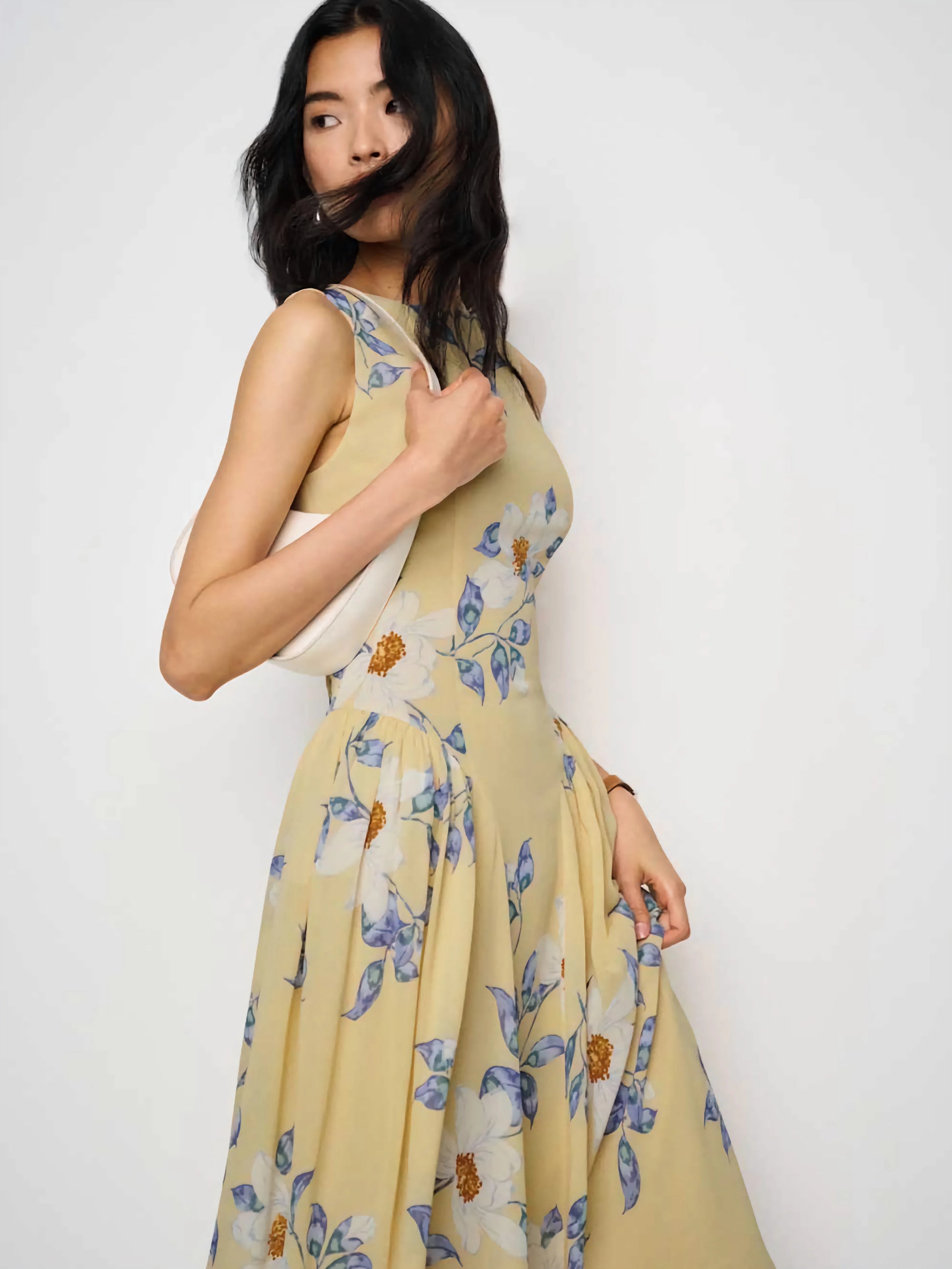 Woman wearing a yellow floral dress against a white background