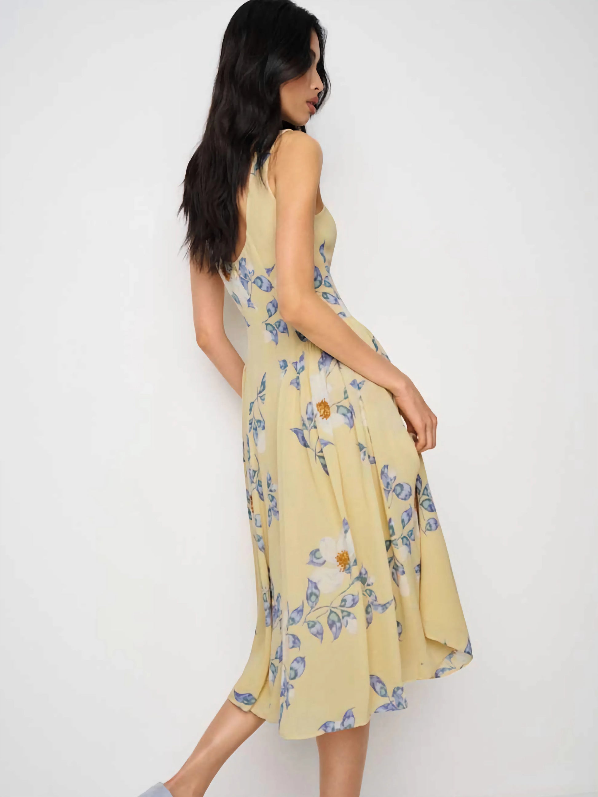 Woman wearing a yellow floral dress on a white background