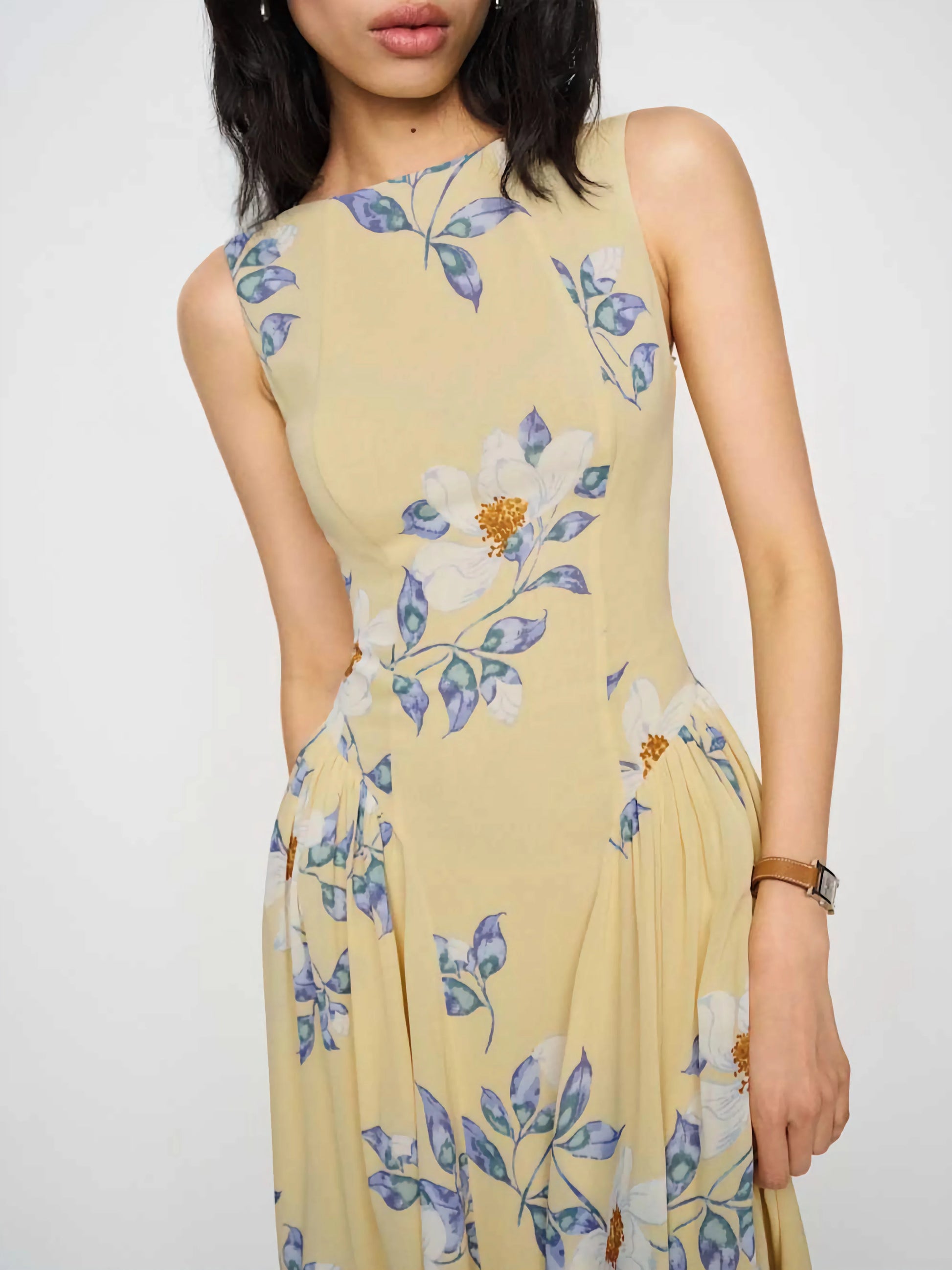 Woman wearing a yellow floral dress against a white background