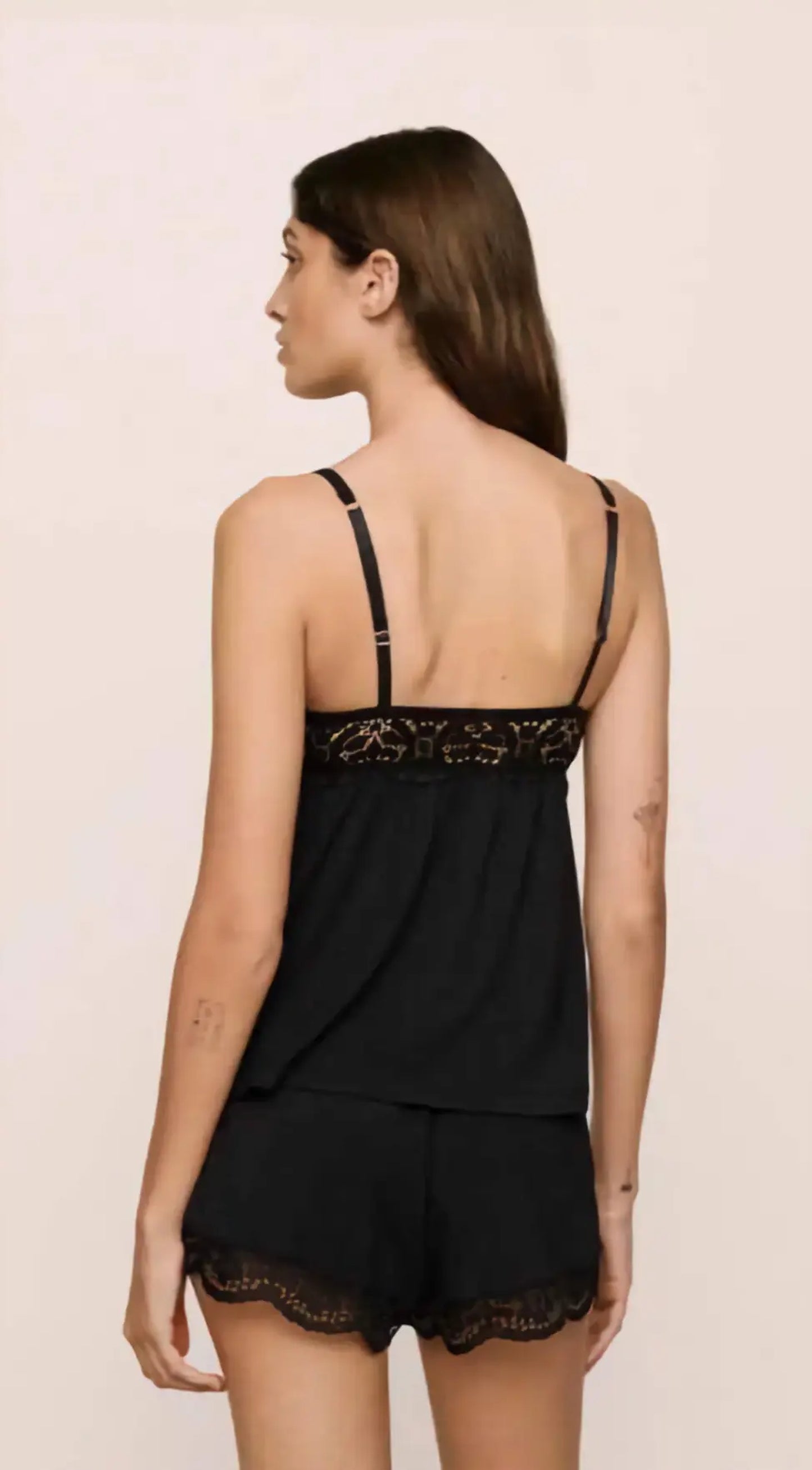 Woman wearing a black lace lingerie set against a beige background