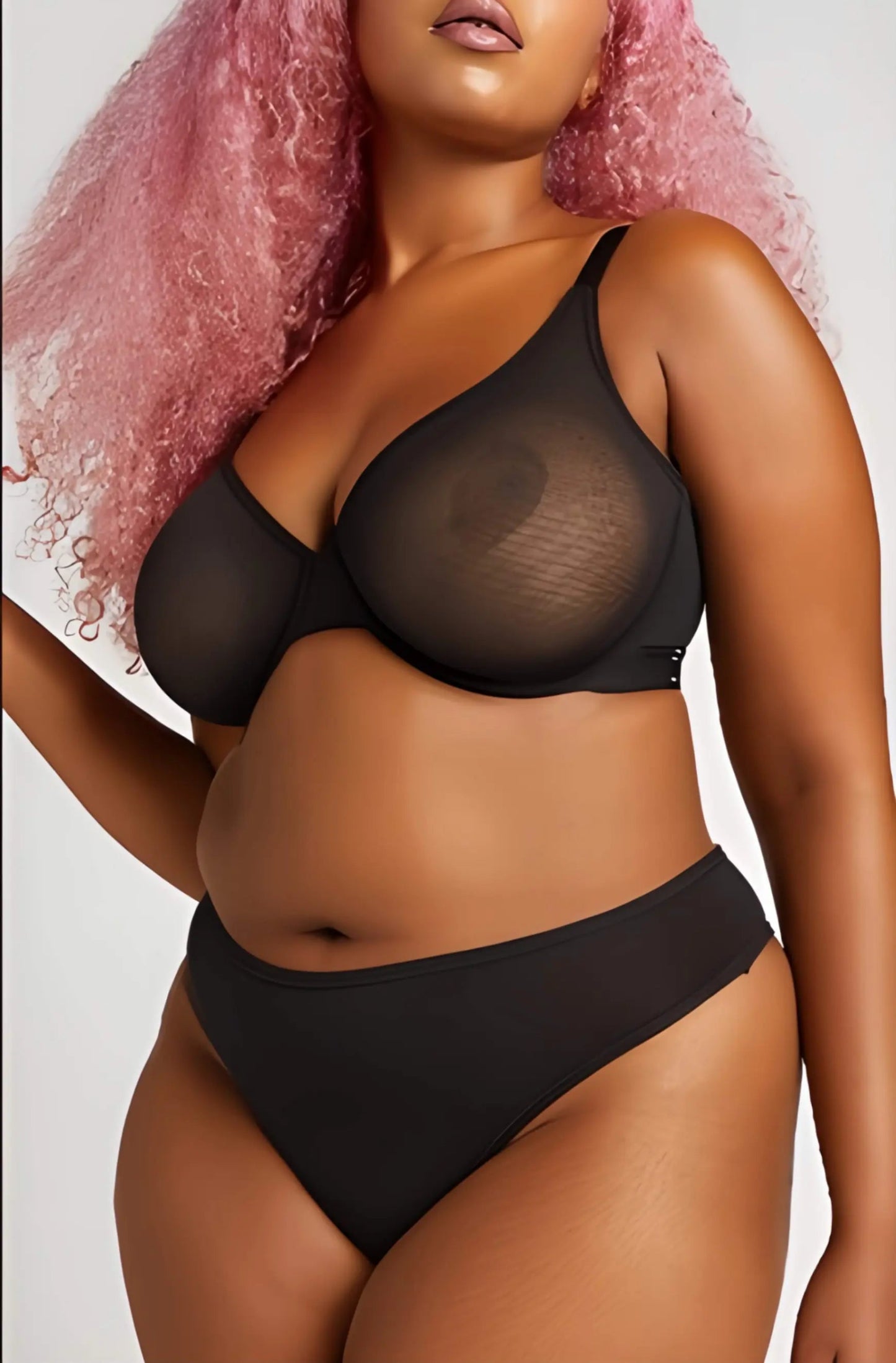 Person wearing a black lingerie set with a plain background