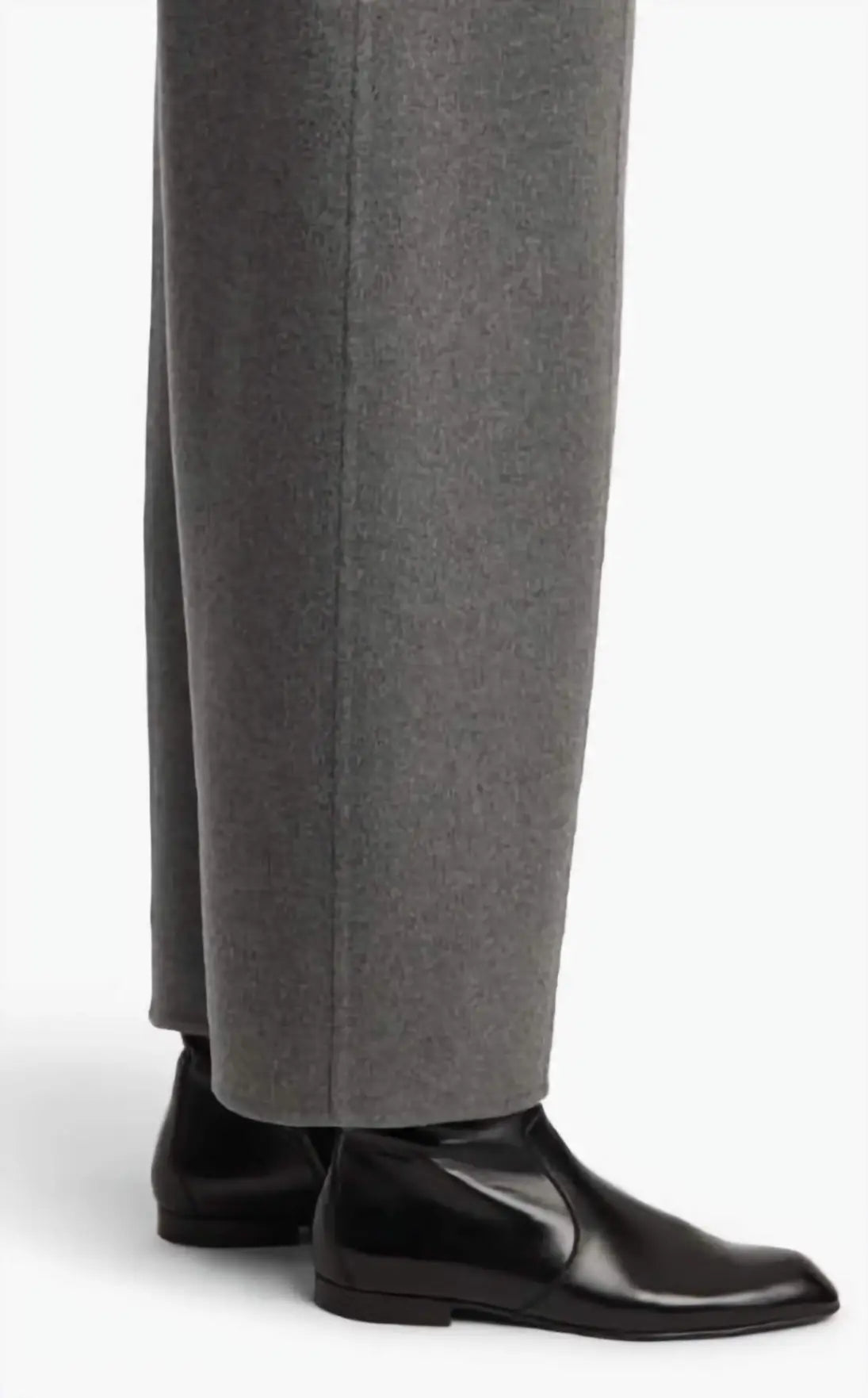 Person wearing gray pants and black shoes on a white background
