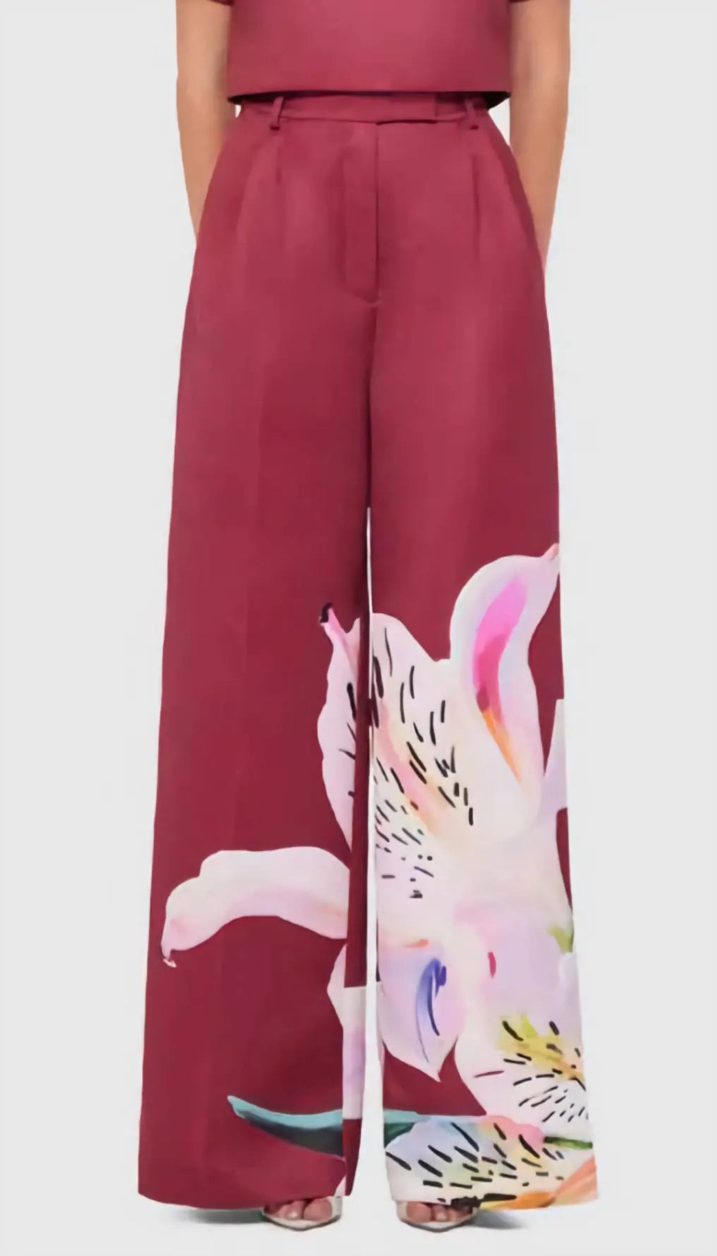 Maroon pants with a colorful abstract design worn by a person on a white background