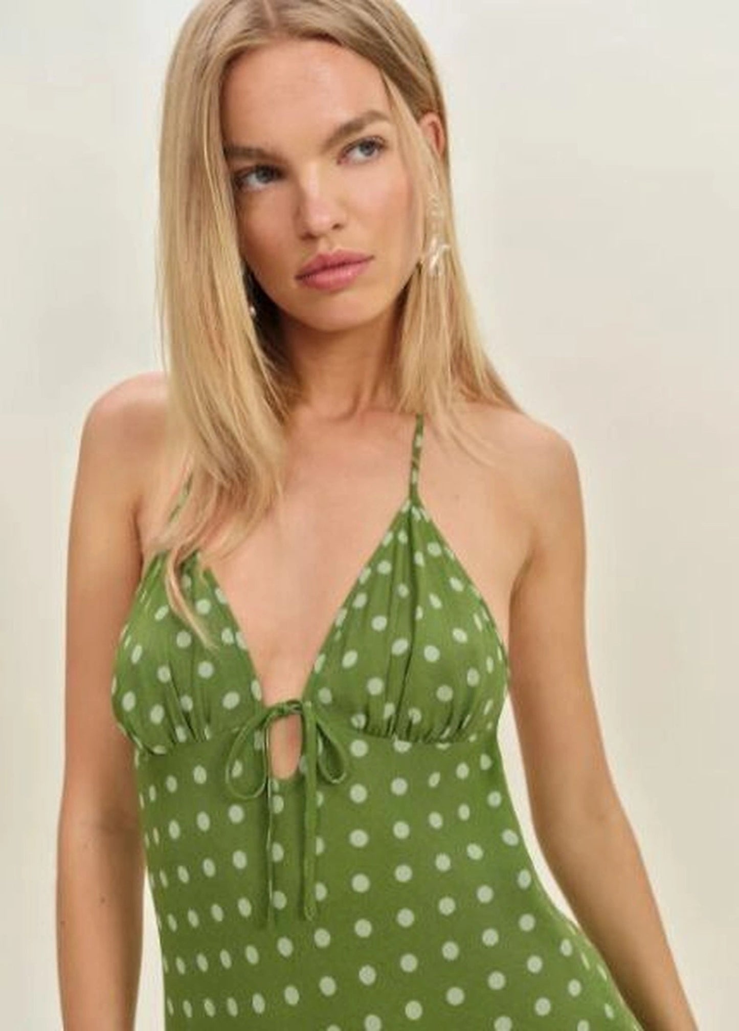Fiora Dress in black LENZING™ ECOVERO™ viscose crepe, showcasing its halter neckline and empire silhouette on a woman in a summer setting.